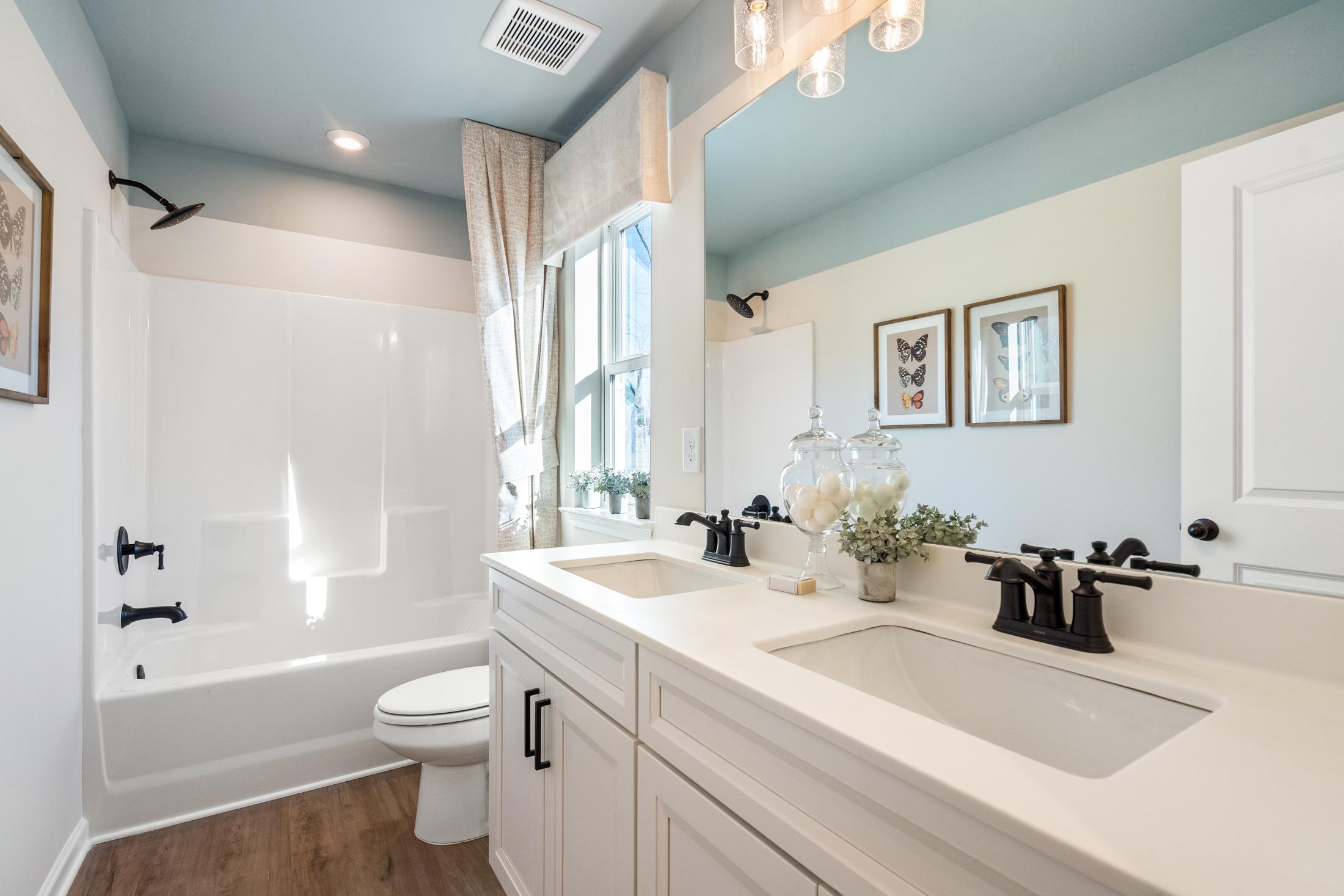 Spacious master bathroom in The Marion A with double vanity, soaking tub, walk-in shower, and blue ceiling