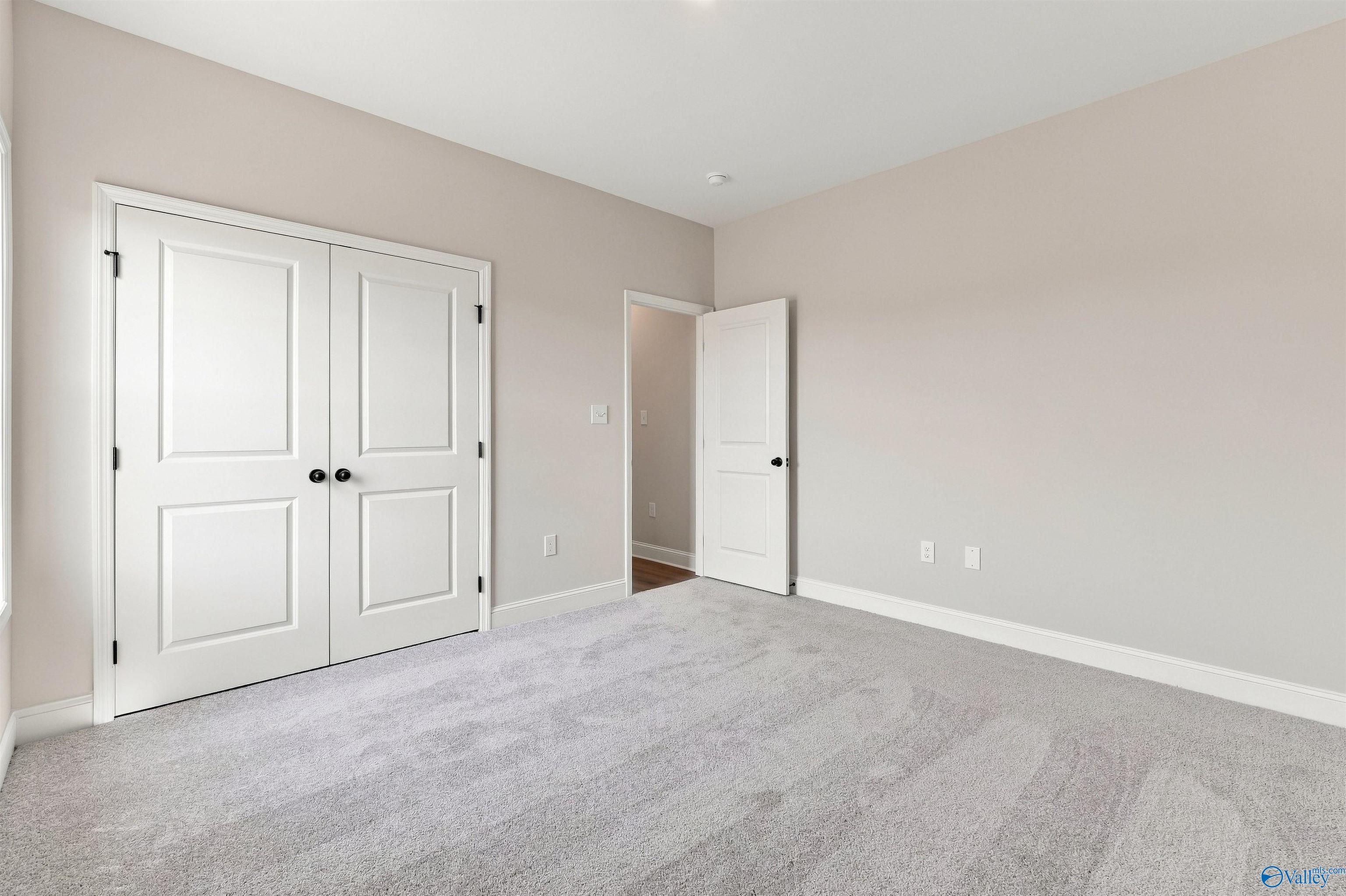 Spacious bedroom with grey carpet, walk-in closet, and neutral walls in The Oxford floor plan at Kendall Farms, Toney, AL.