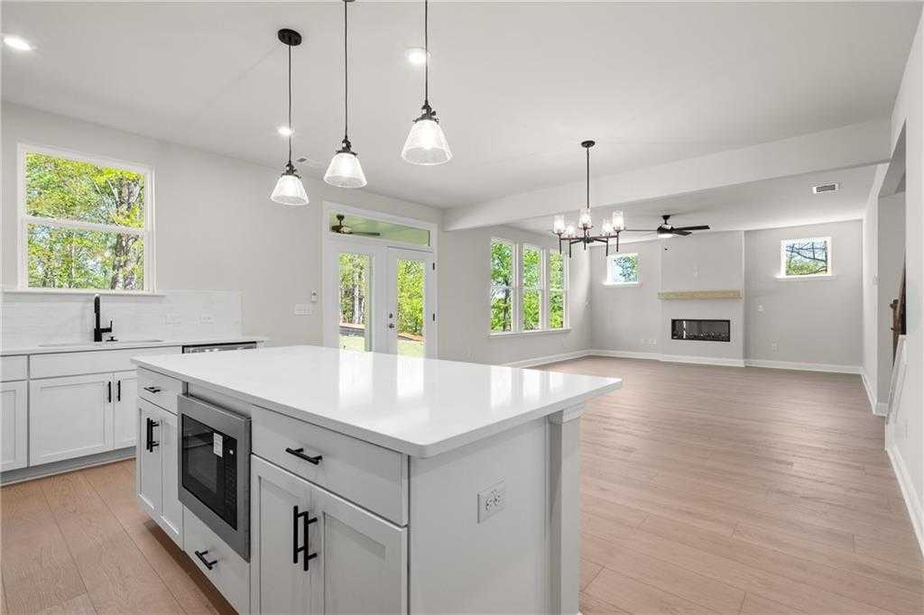 Open-concept kitchen-living room with white shaker cabinets, quartz island, gas fireplace in Davidson Homes The Hickory B, Buford, GA