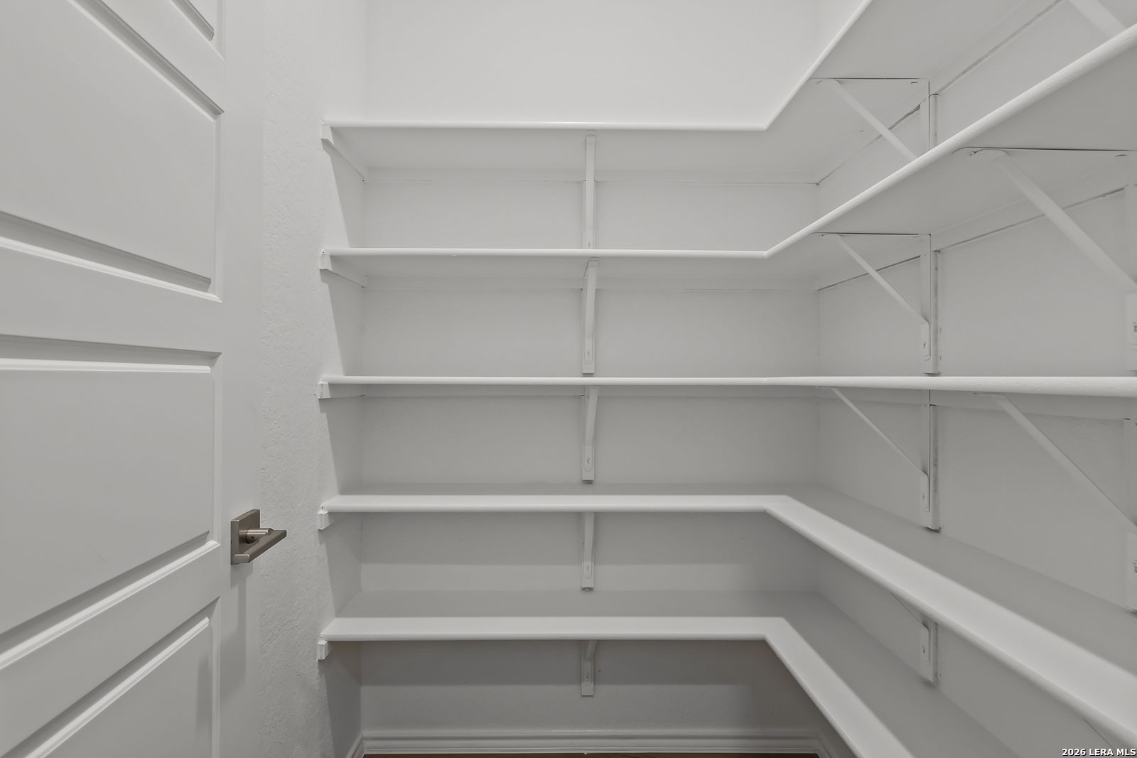 Spacious walk-in closet with white built-in corner shelving in Davidson Homes The Sequoia B, San Antonio
