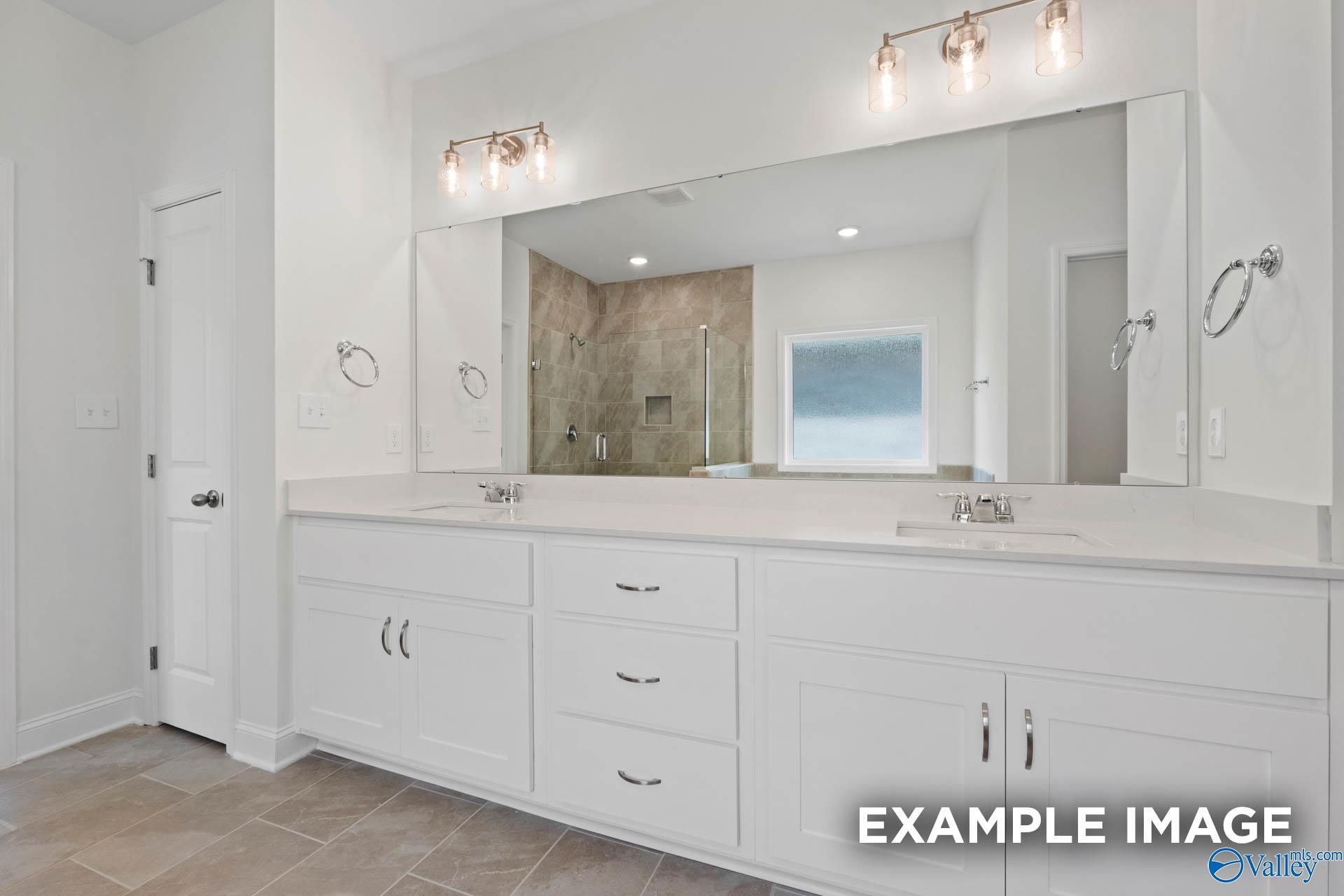 Elegant master bathroom with double vanity, frameless glass shower, and window in Davidson Homes The Oxford, Huntsville AL