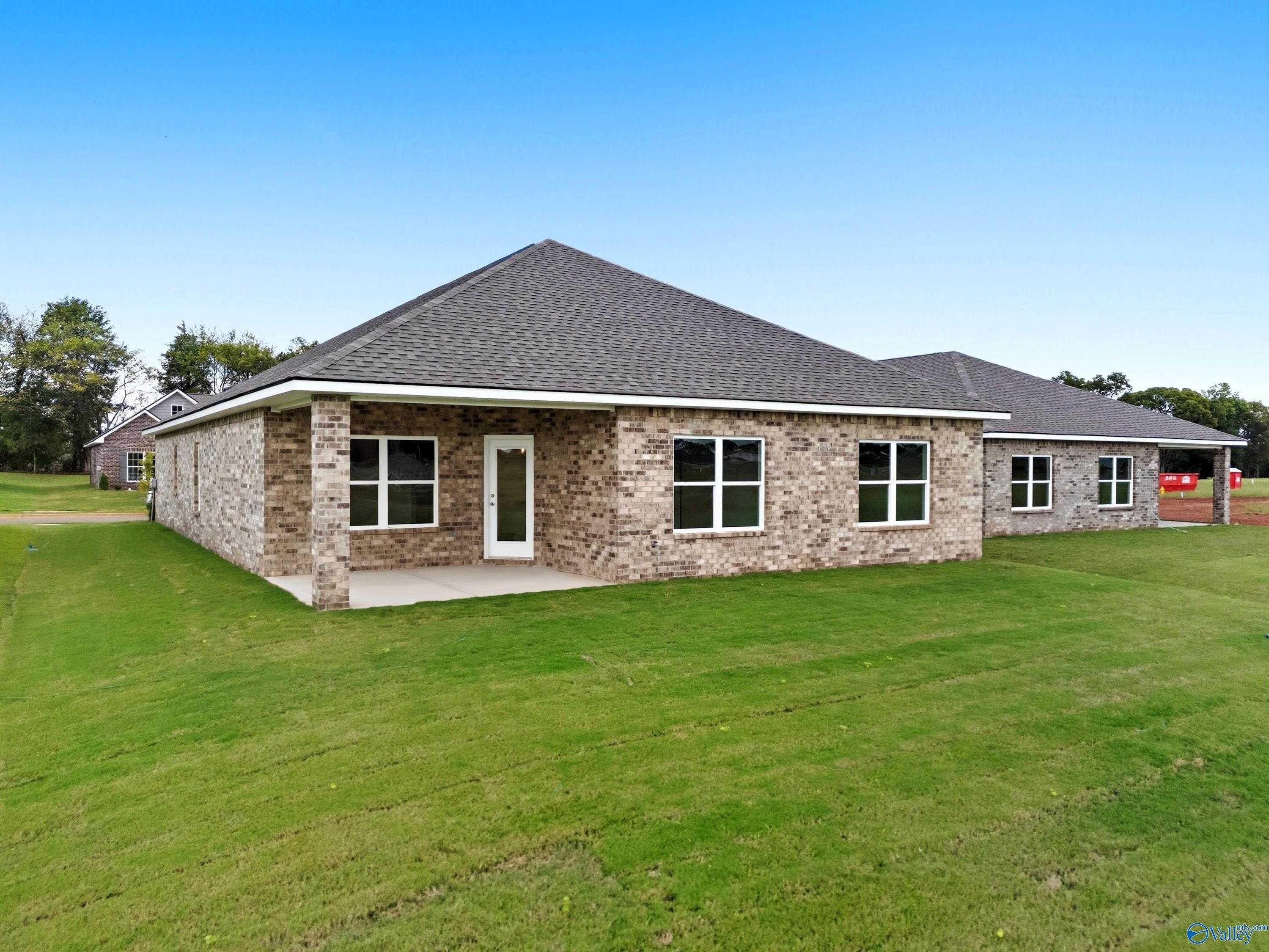 Brick single-story 4-bedroom home, The Everett floor plan by Davidson Homes, front elevation with white door and lush green lawn in Lynn Meadows, Meridianville, Alabama