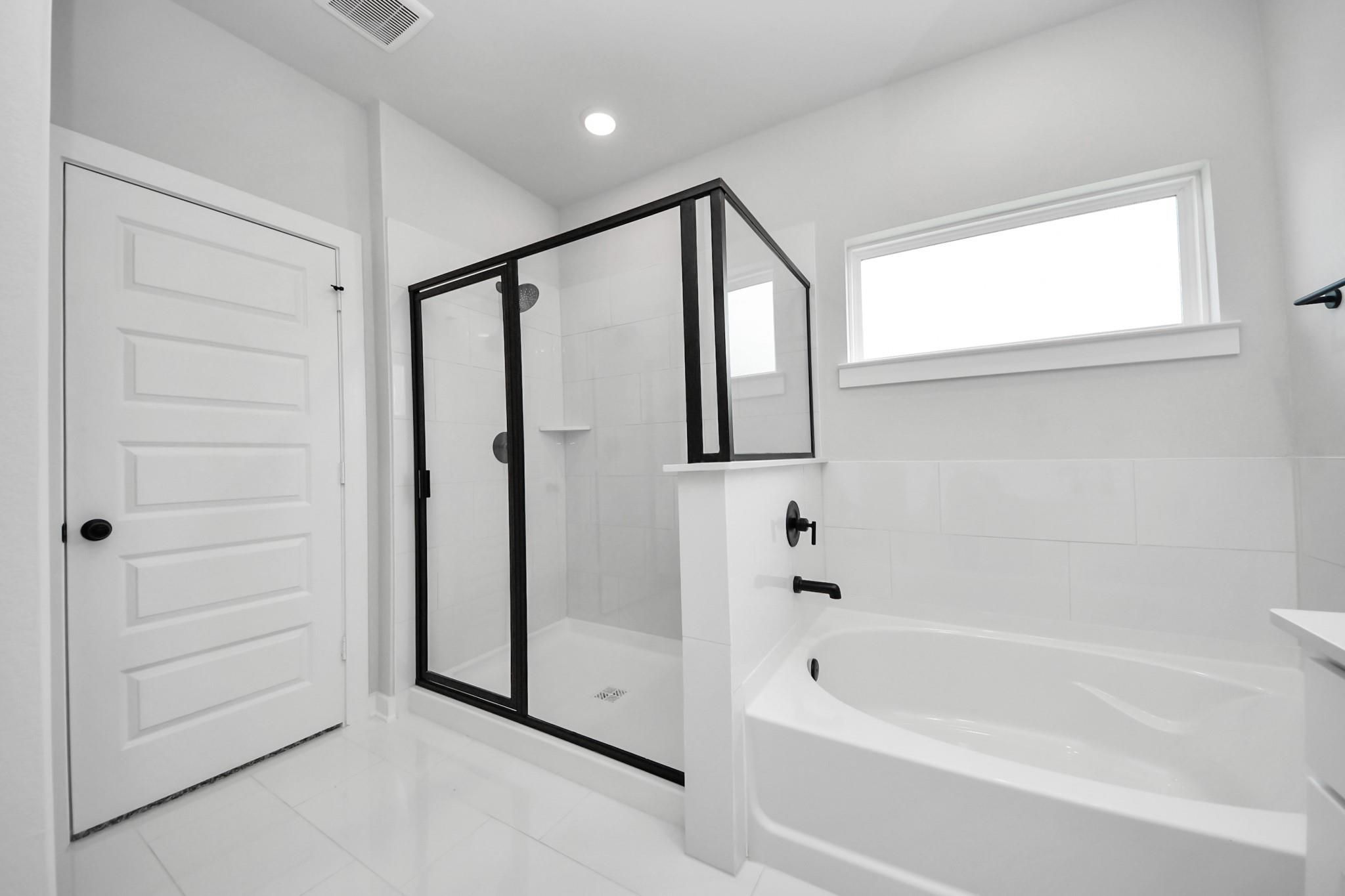 Modern master bathroom with glass-enclosed shower and soaking tub in The Riviera C home at River Ranch Meadows, Dayton.