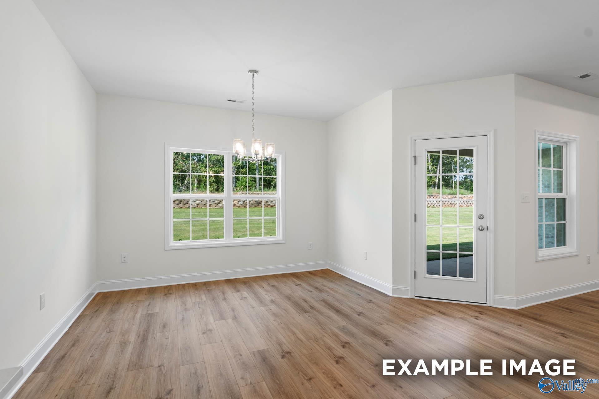 Bright dining room with hardwood floors, chandelier, large windows to lush lawn, and patio door in Davidson Homes Rockford C, Madison, Alabama