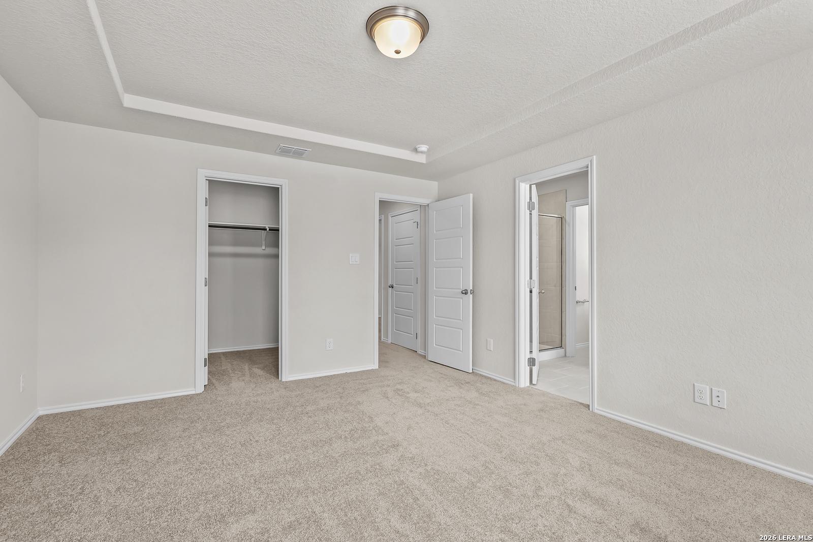 Spacious secondary bedroom with walk-in closet and en-suite bathroom access in The Gillian B floor plan, San Antonio, Texas.