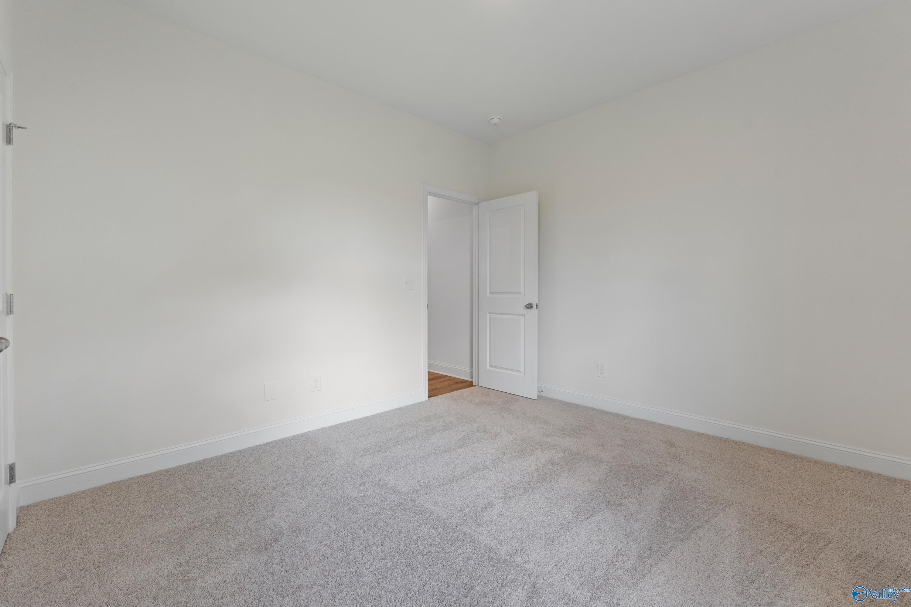 Bright, spacious bedroom with neutral carpet in The Everett B floor plan at The Meadows in Athens, Alabama.