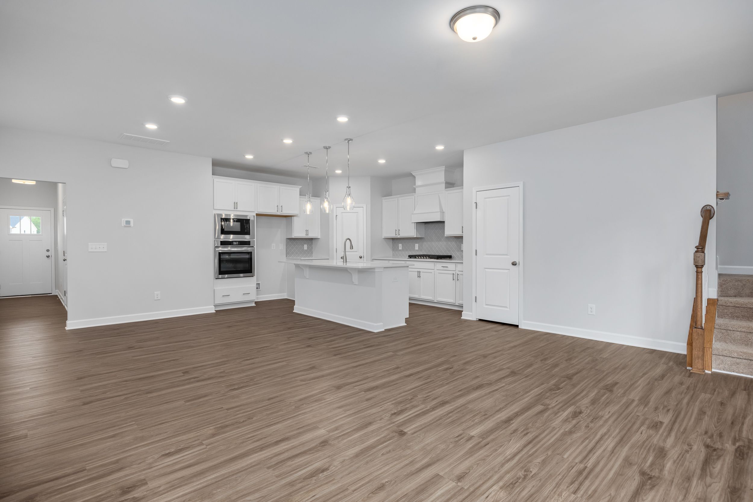 Open-concept kitchen in The Durham featuring white cabinetry, a center island, and modern stainless steel wall oven.