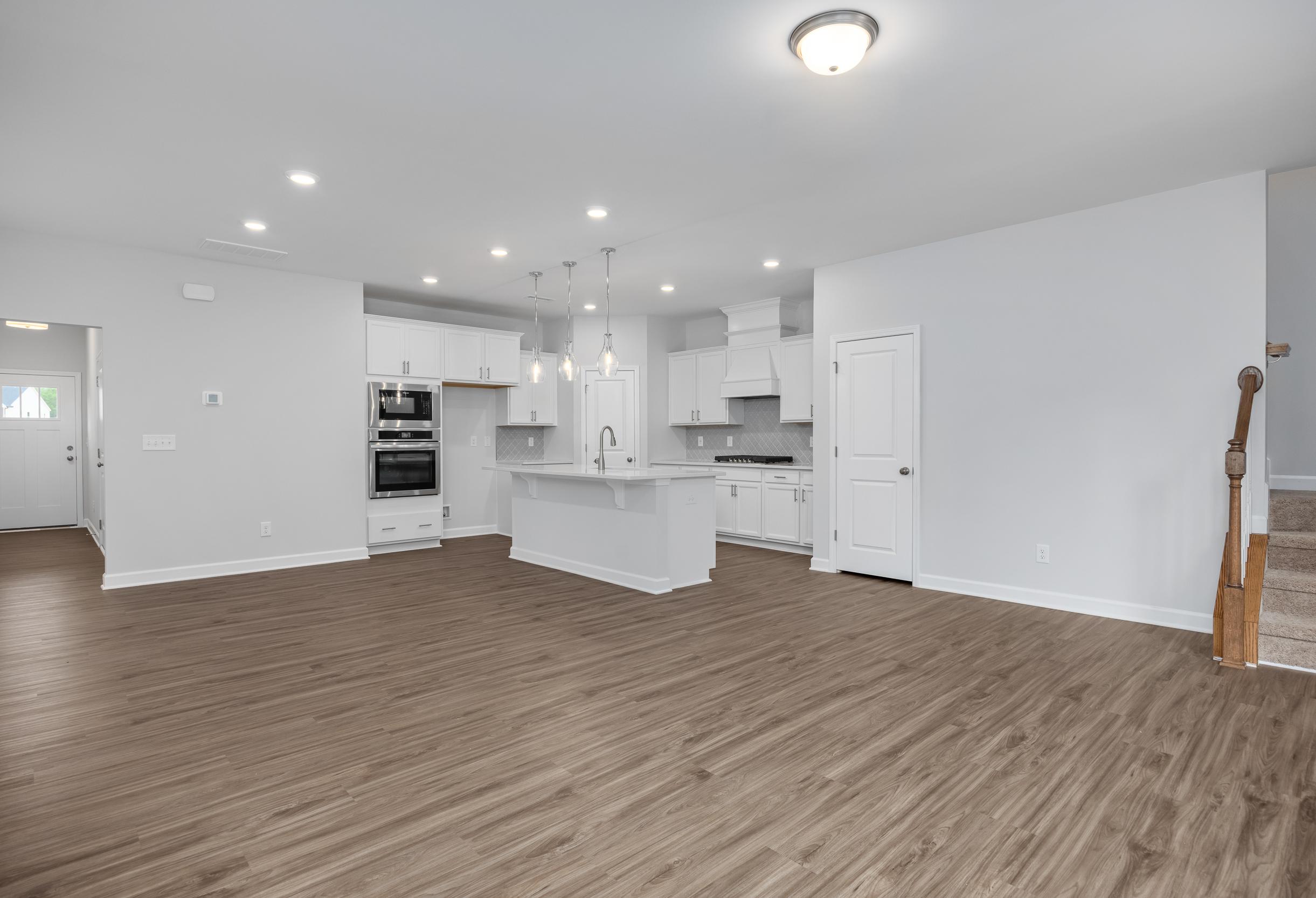 Open-concept kitchen in The Durham featuring white cabinetry, a center island, and modern stainless steel wall oven.