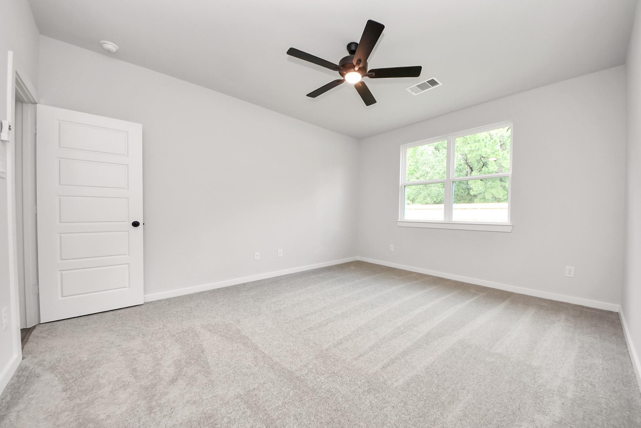 Bright, carpeted bedroom with ceiling fan in The Daphne F floor plan at Sundance Cove, Crosby, Texas.