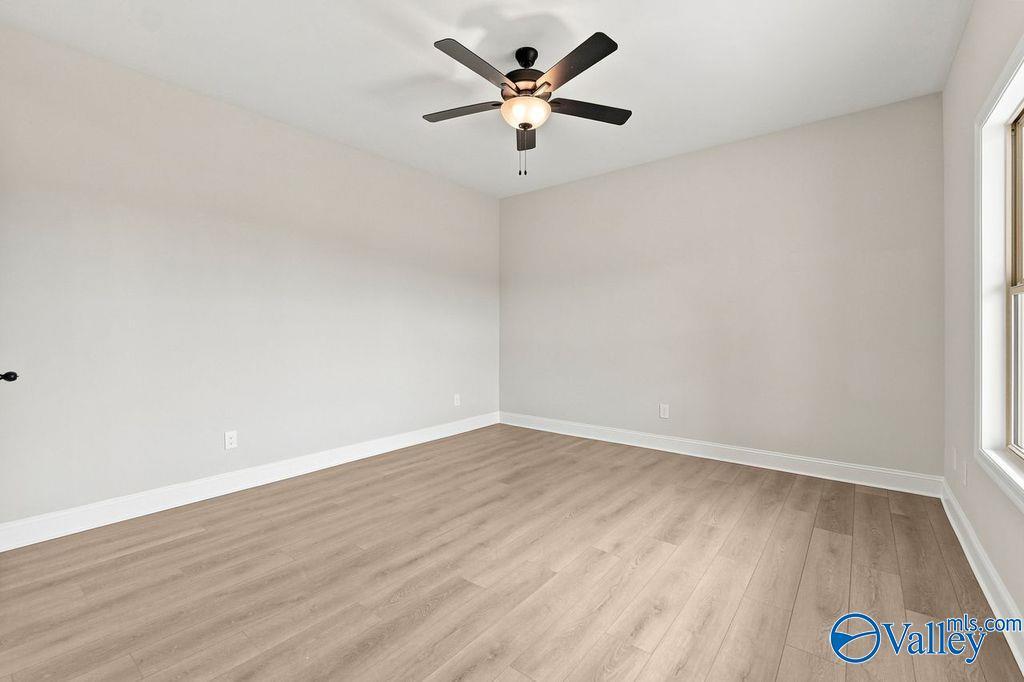 Bright bedroom with neutral walls, wood-style flooring, and ceiling fan in The Camilla B floor plan, Hartselle, Alabama.