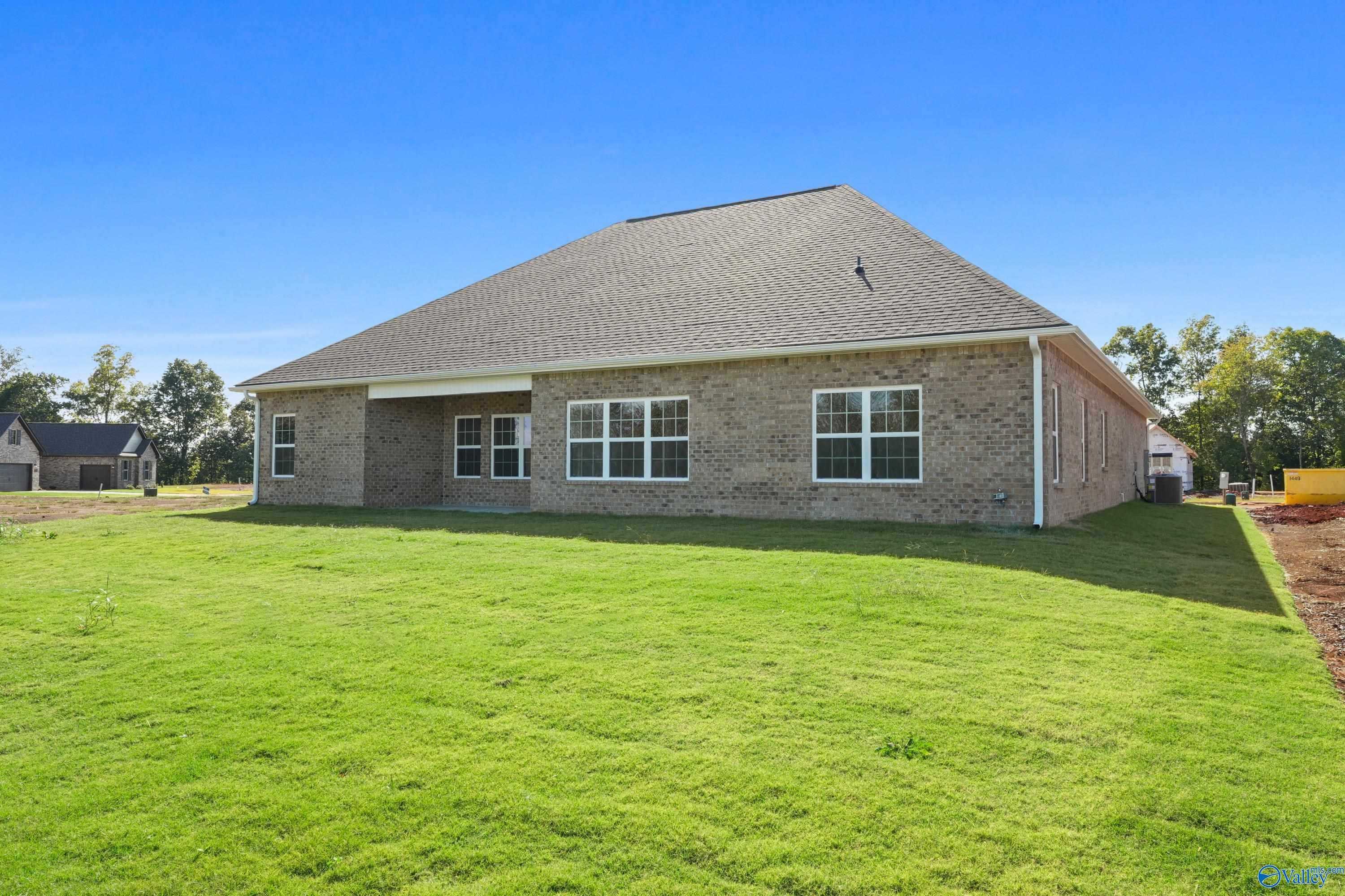 Brick Finleigh home rear view with covered patio, large windows, lush green yard in Creekside, Harvest, Alabama by Davidson Homes