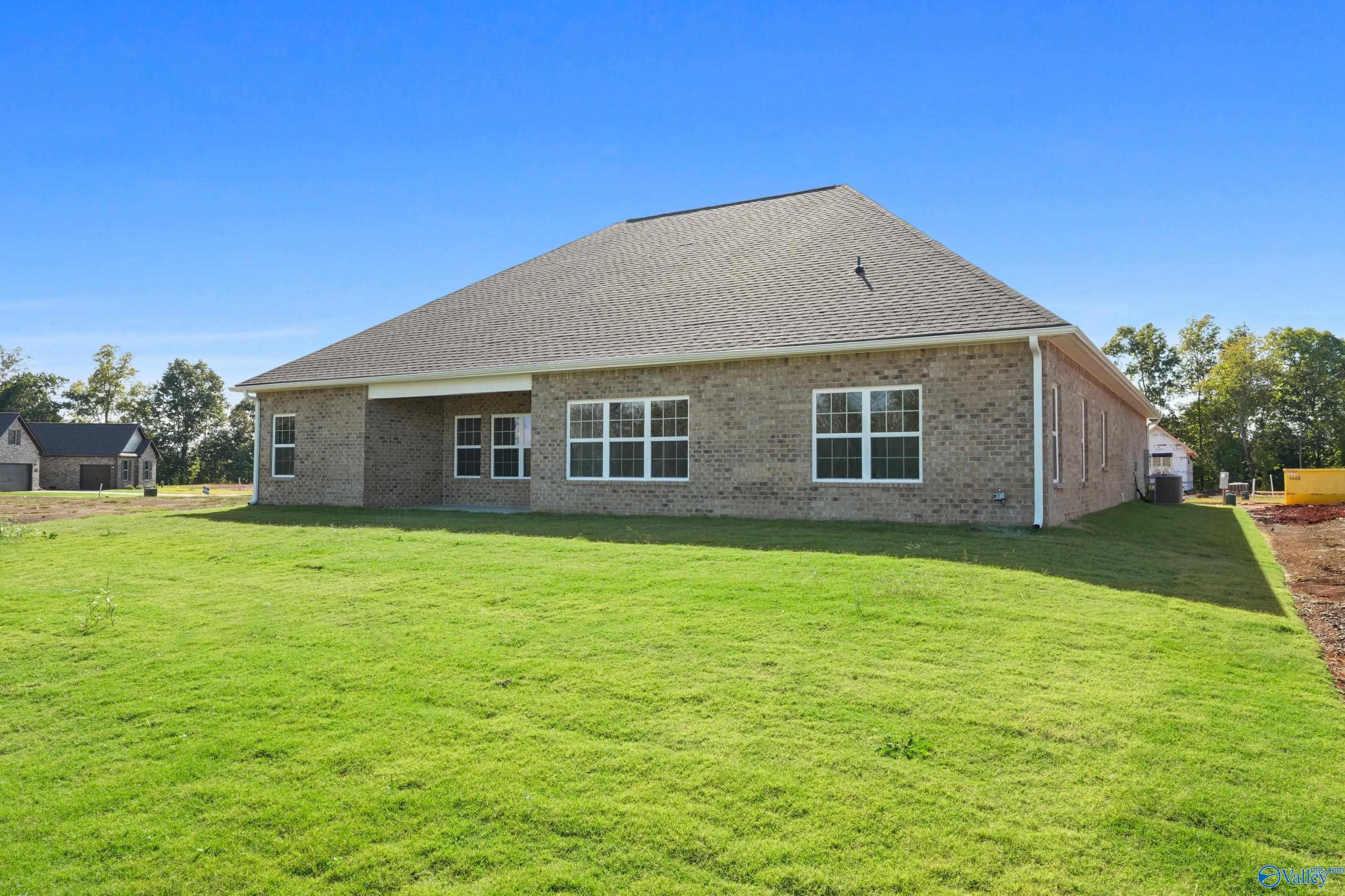 Brick Finleigh home rear view with covered patio, large windows, lush green yard in Creekside, Harvest, Alabama by Davidson Homes