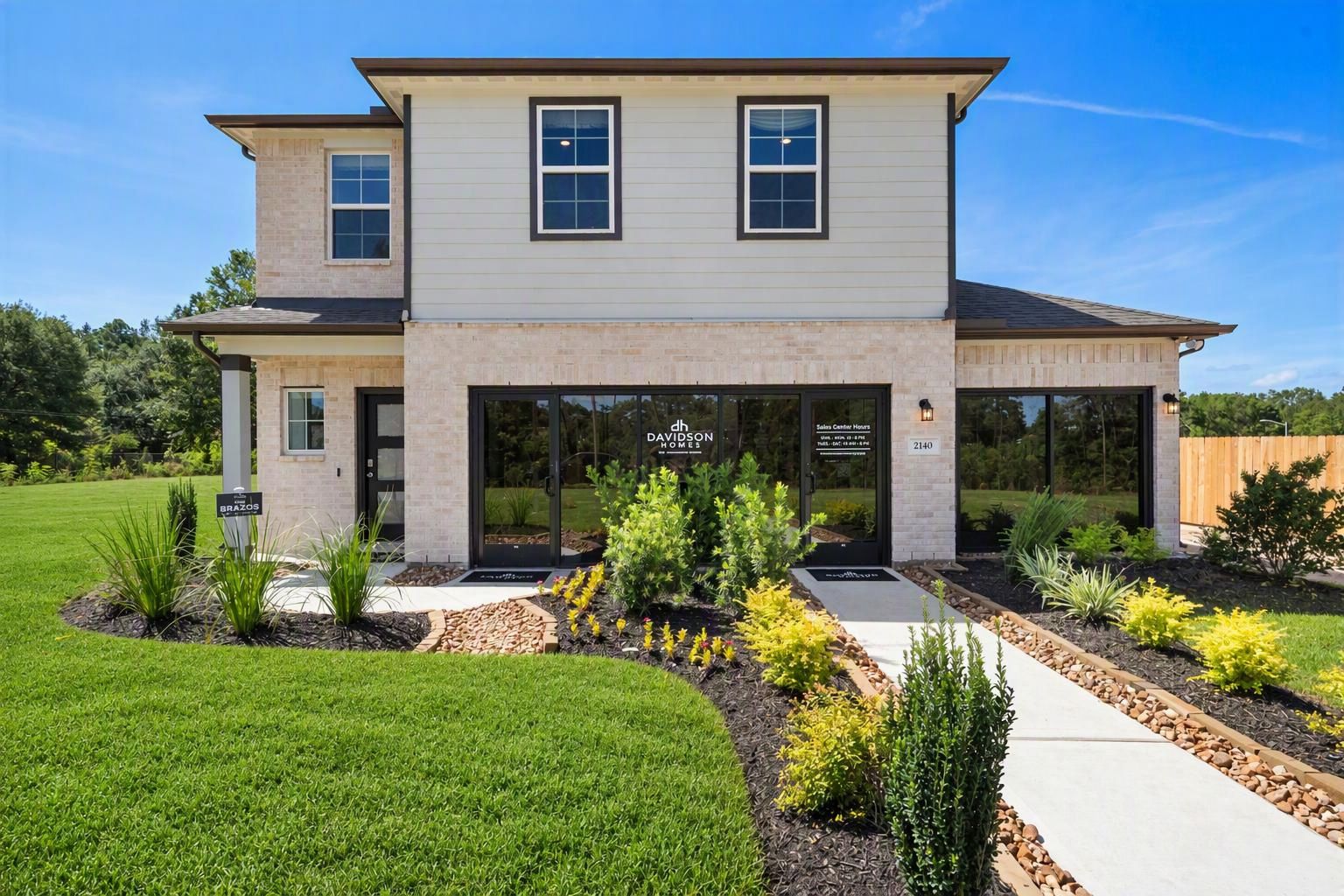 Spacious living room in Caney Creek Place Conroe TX with beige sectional sofa, emerald green velvet chairs, hardwood floors, ceiling fan, and modern art