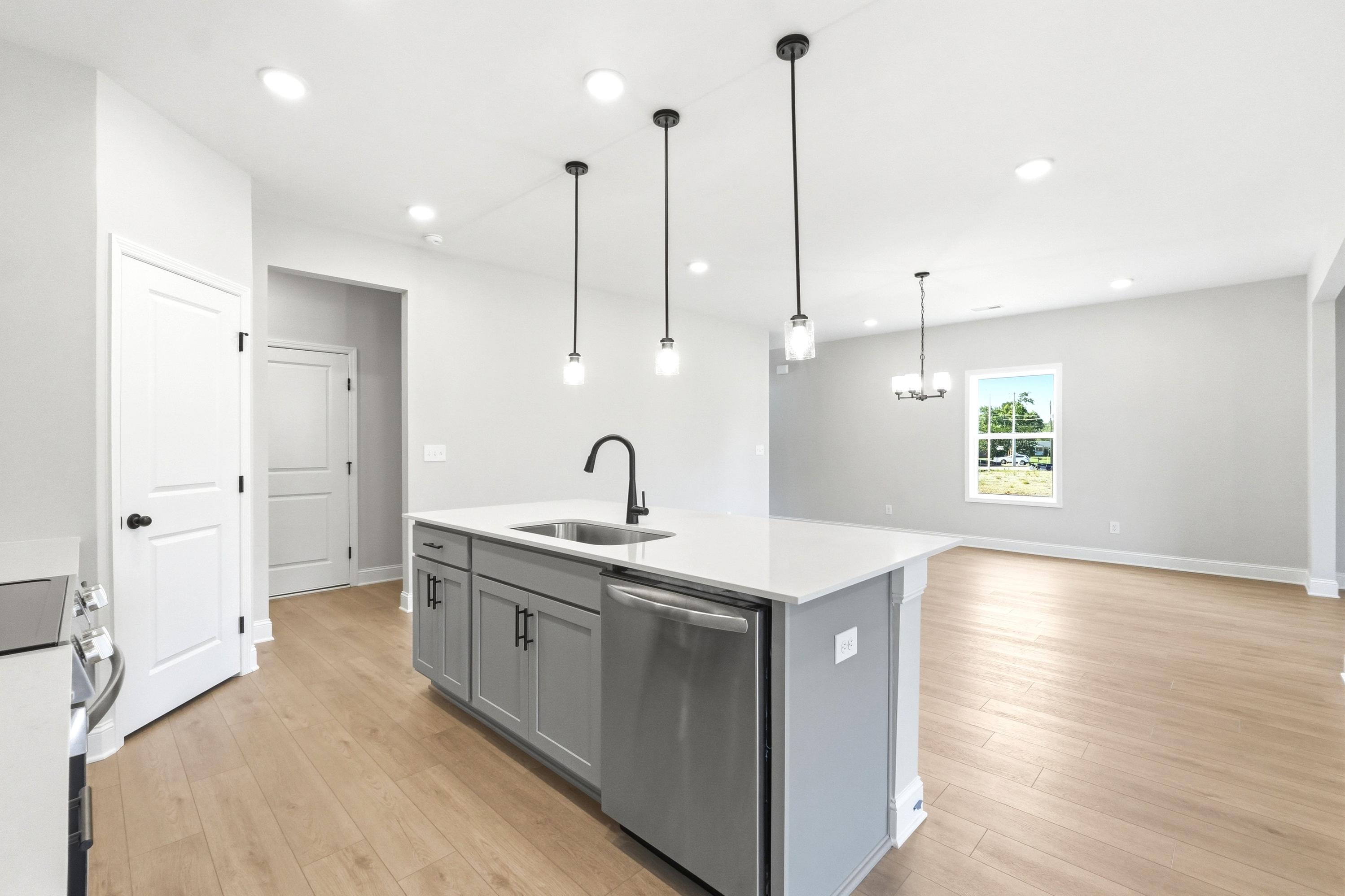 Modern kitchen island with quartz countertops and pendant lighting in The Russell A floor plan by Davidson Homes.