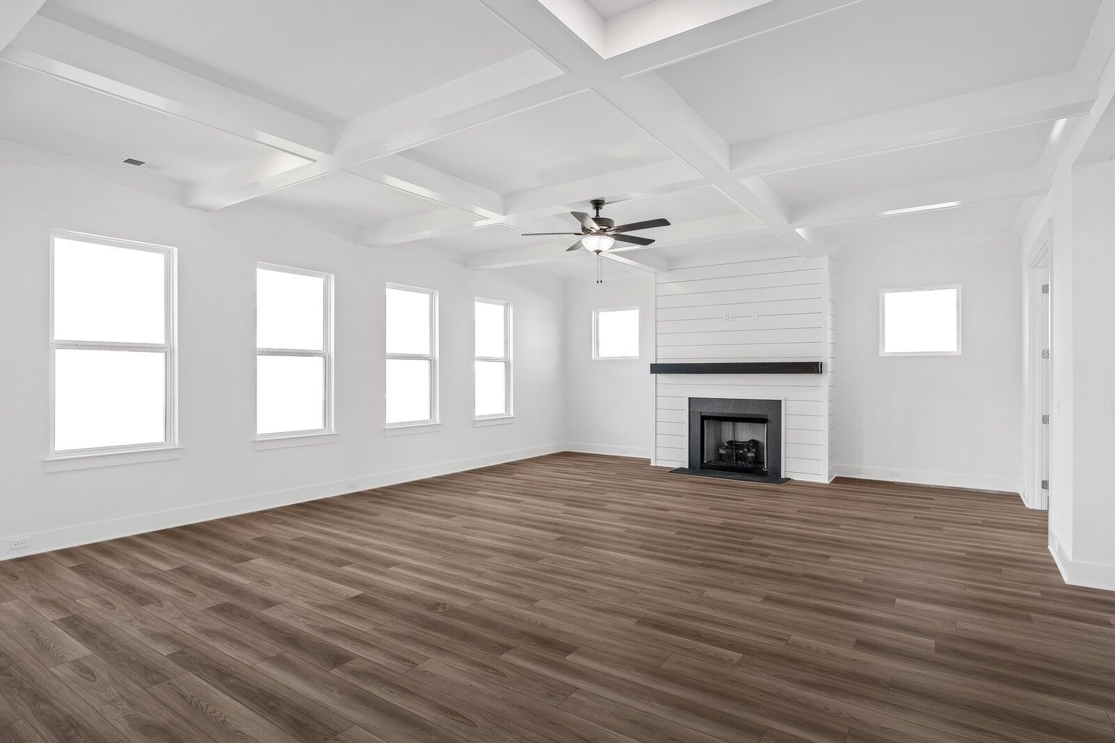 Spacious living room featuring shiplap fireplace, coffered ceiling fan, large windows, and hardwood floors in Davidson Homes The Alston A, Murfreesboro, TN
