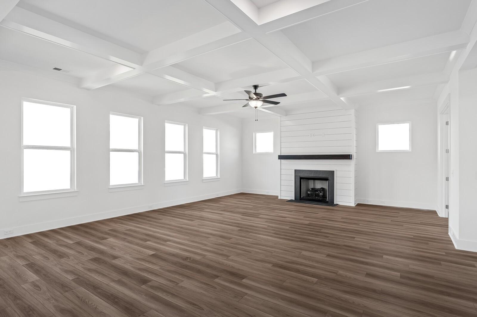 Spacious living room featuring shiplap fireplace, coffered ceiling fan, large windows, and hardwood floors in Davidson Homes The Alston A, Murfreesboro, TN