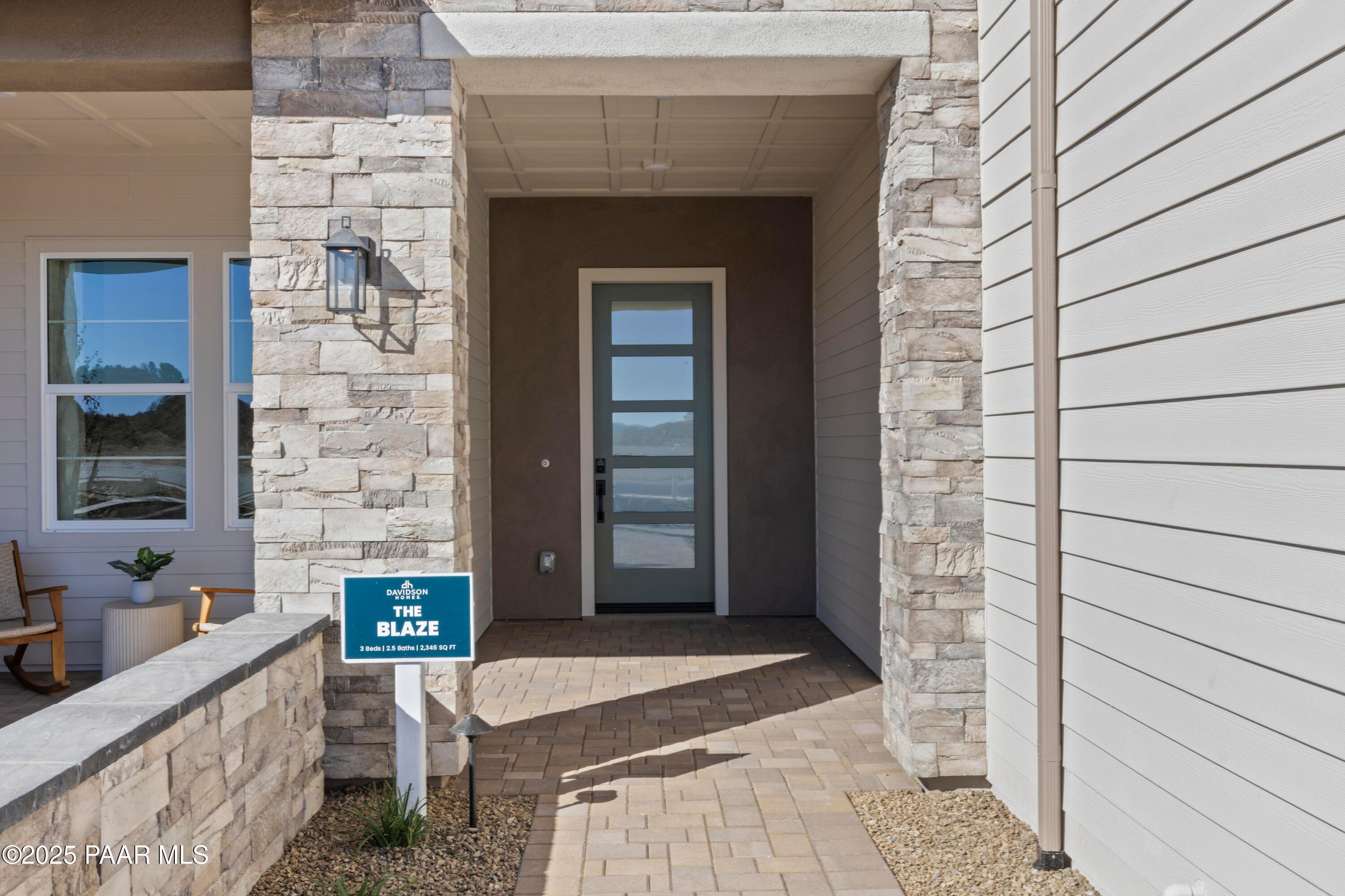 Modern front entrance with stone pillars, glass door, and Davidson Homes sign for The Blaze D 3-bedroom home in Hidden Hills, Prescott, Arizona