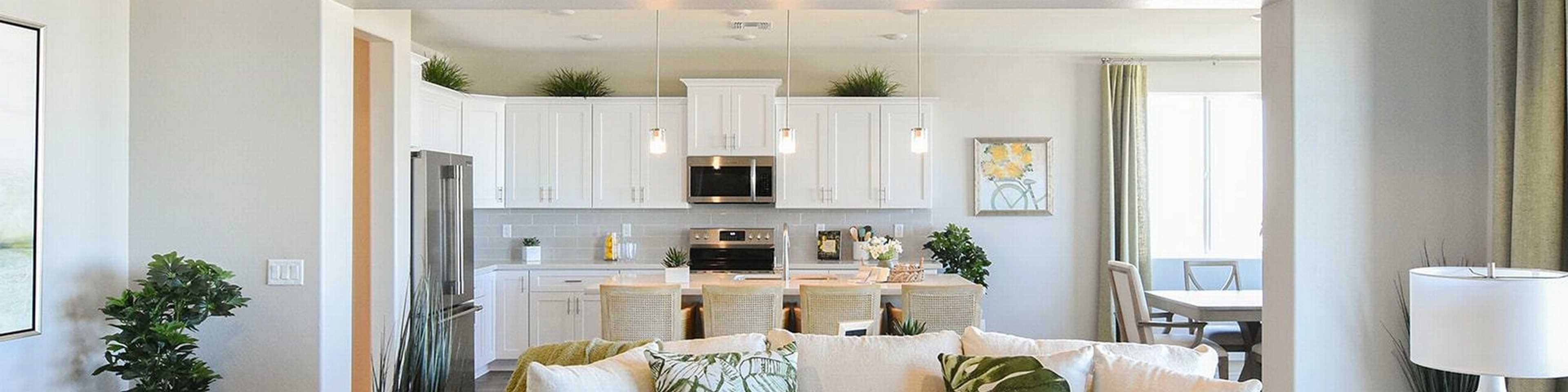 Open-concept living and kitchen at Morningstar in Prescott Valley AZ by Evermore Homes with vaulted ceilings, white cabinets, and beige sofa