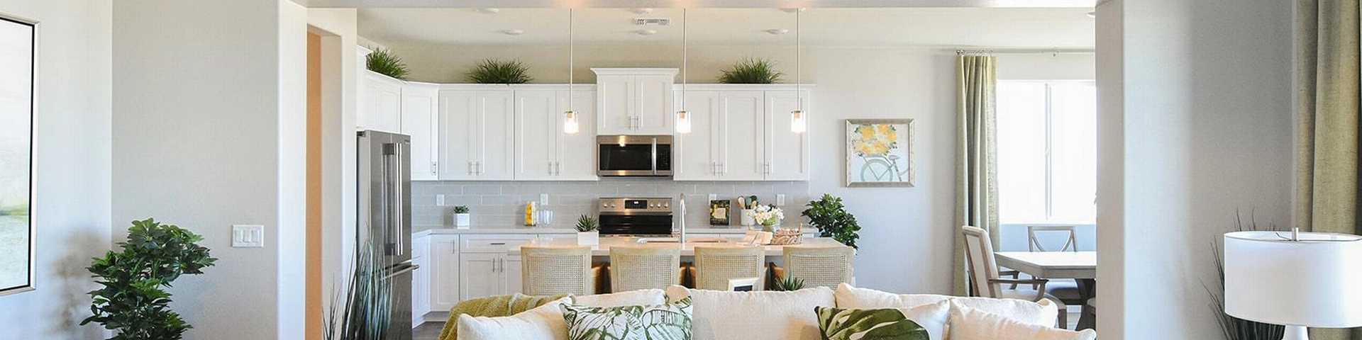 Open-concept living and kitchen at Morningstar in Prescott Valley AZ by Evermore Homes with vaulted ceilings, white cabinets, and beige sofa