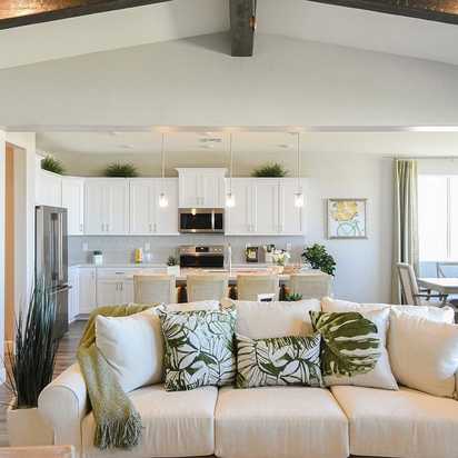 Open-concept living and kitchen at Morningstar in Prescott Valley AZ by Evermore Homes with vaulted ceilings, white cabinets, and beige sofa