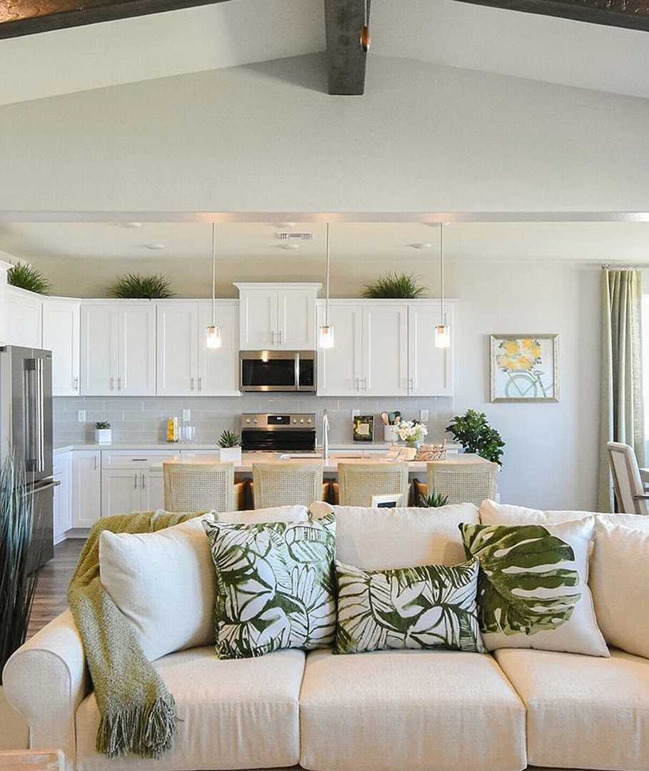 Open-concept living and kitchen at Morningstar in Prescott Valley AZ by Evermore Homes with vaulted ceilings, white cabinets, and beige sofa