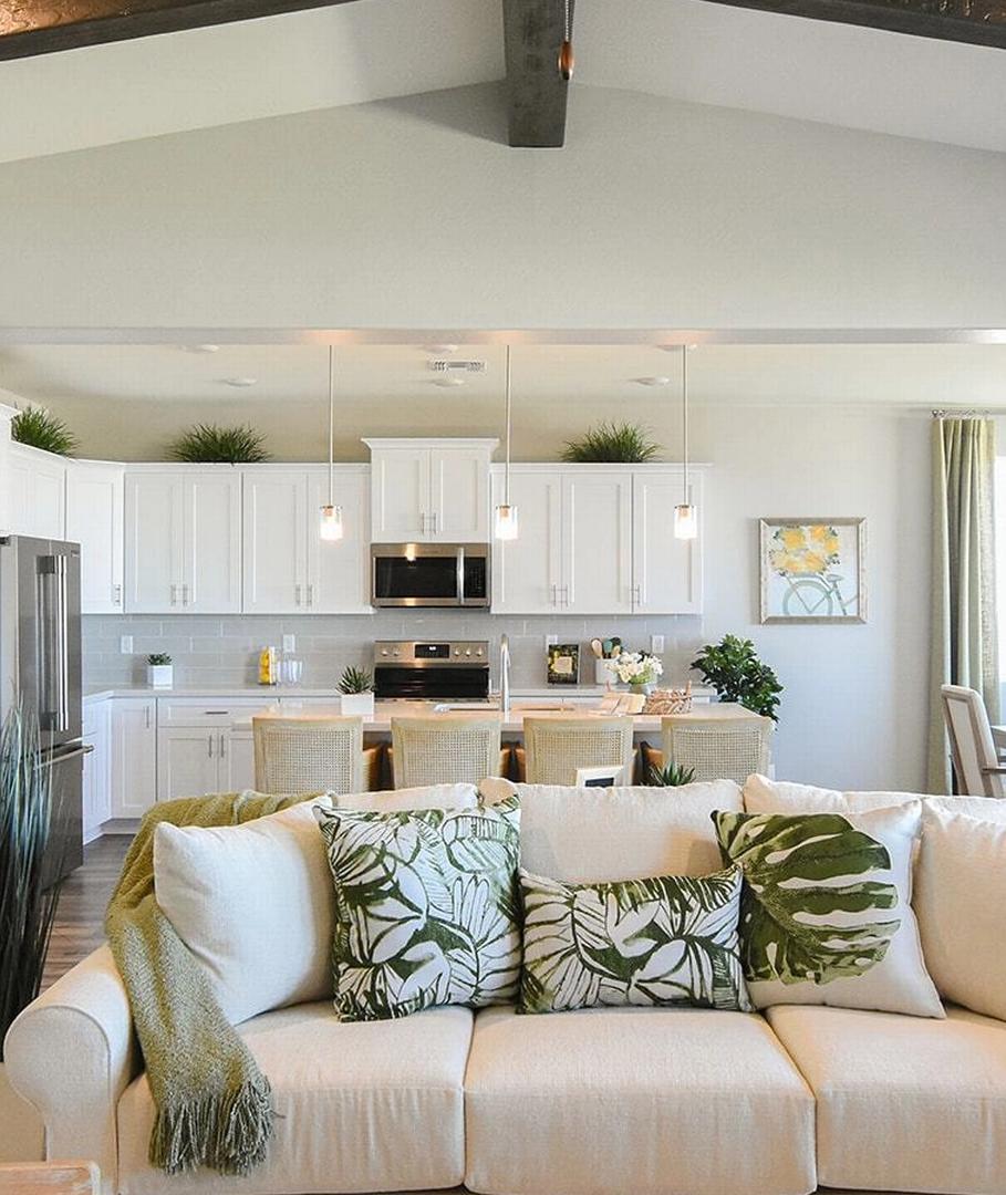 Open-concept living and kitchen at Morningstar in Prescott Valley AZ by Evermore Homes with vaulted ceilings, white cabinets, and beige sofa
