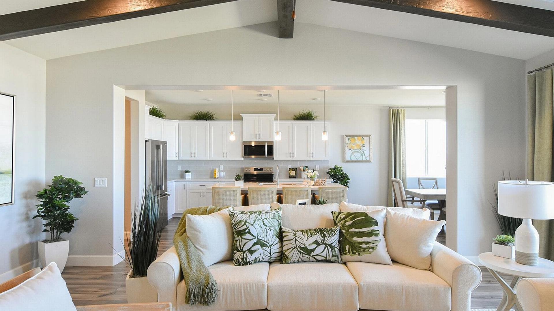 Open-concept living and kitchen at Morningstar in Prescott Valley AZ by Evermore Homes with vaulted ceilings, white cabinets, and beige sofa