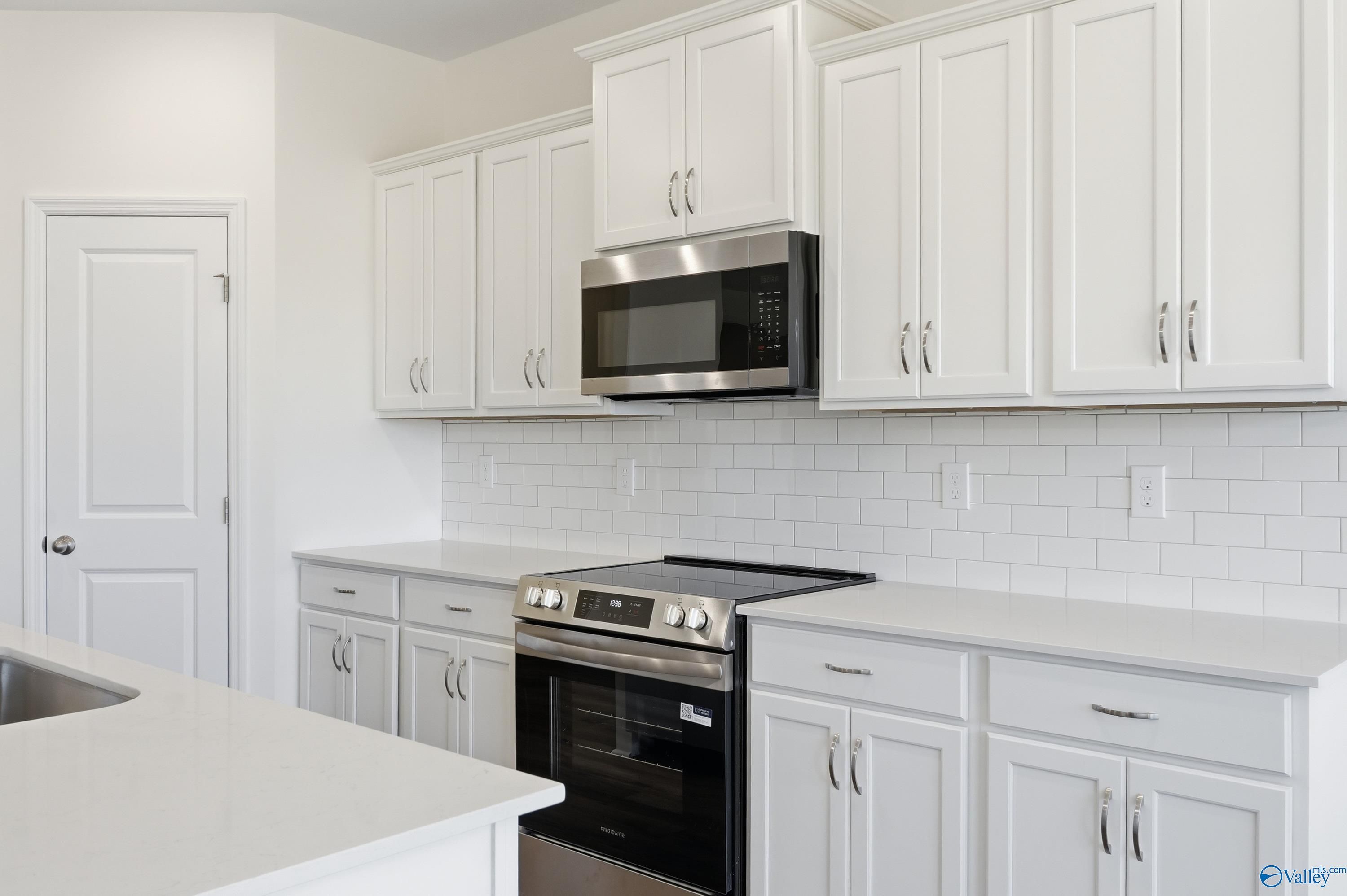 Modern white kitchen with stainless steel appliances, subway tile backsplash, quartz counters in Davidson Homes The Montgomery, Meridianville AL