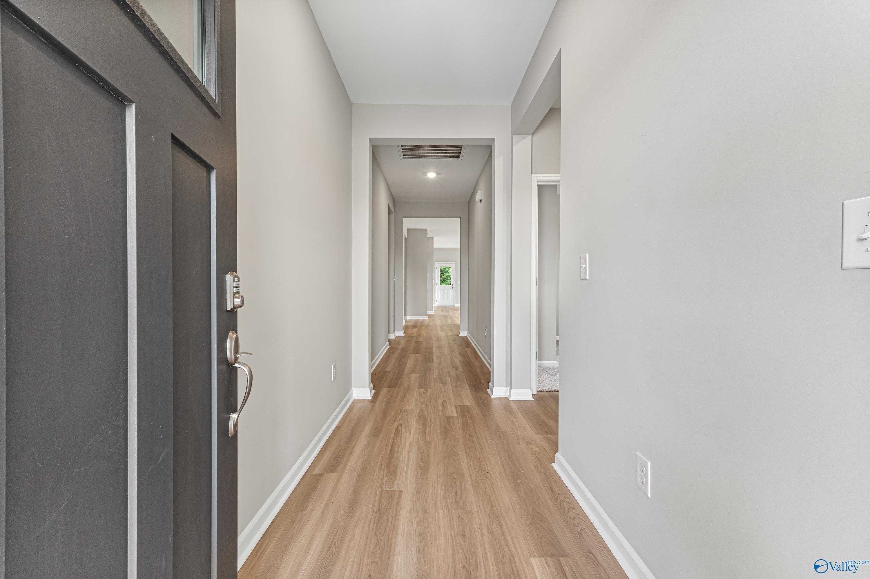 Bright entry hallway with hardwood floors and bedroom doors in Davidson Homes The Aurora, Fayetteville, TN