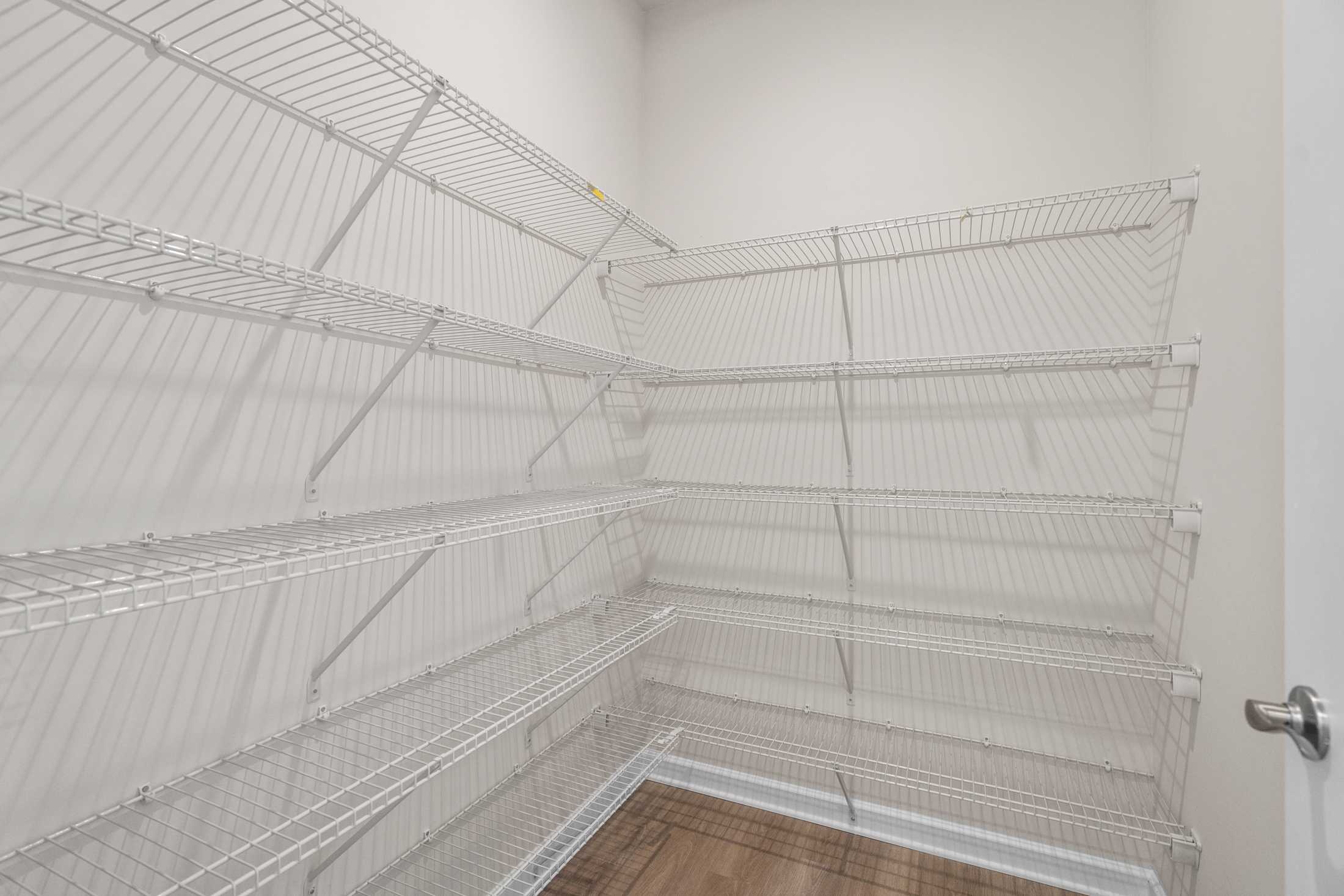 Spacious walk-in closet in The Dawson C with multi-level white wire shelving and hardwood flooring