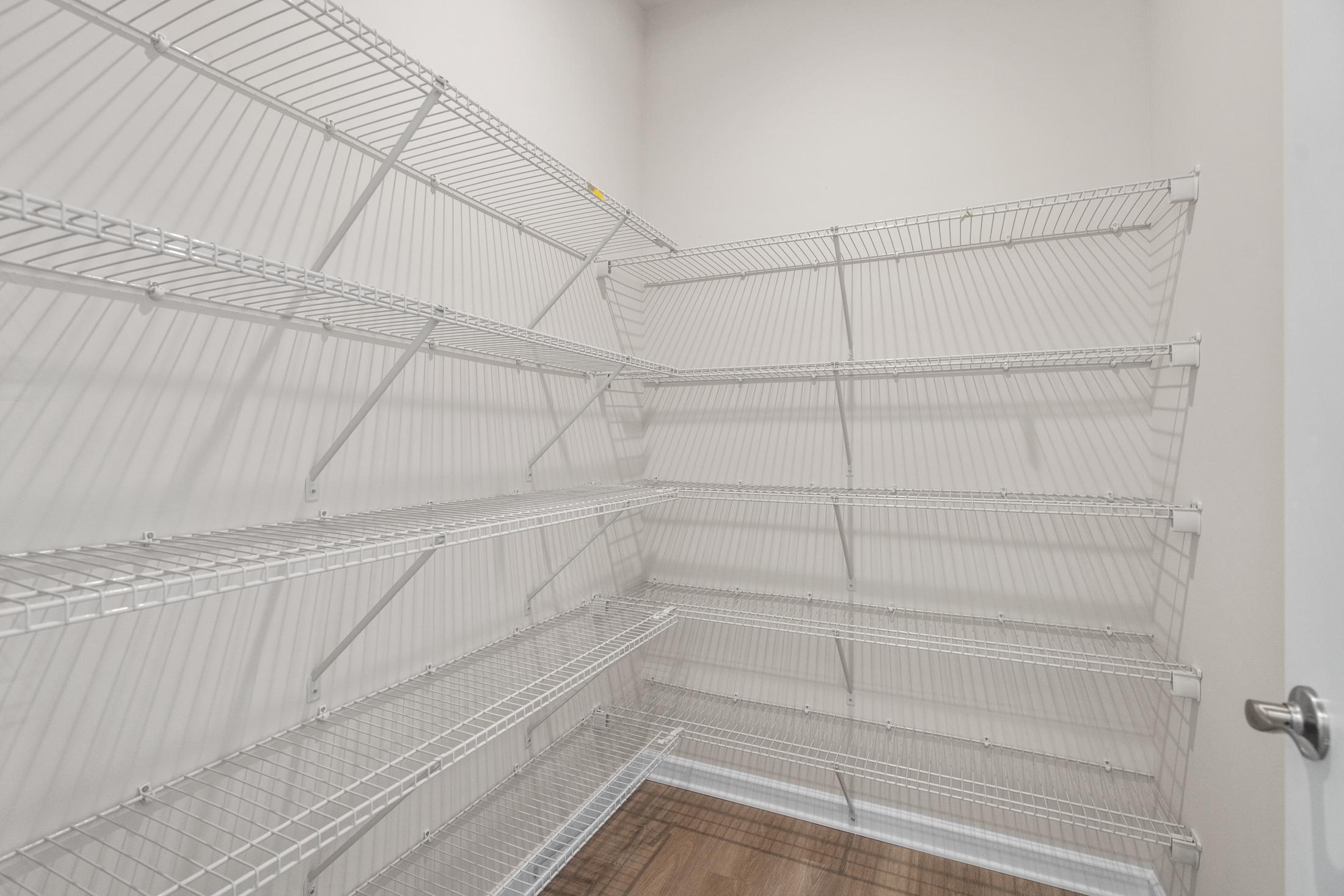 Spacious walk-in closet in The Dawson C with multi-level white wire shelving and hardwood flooring