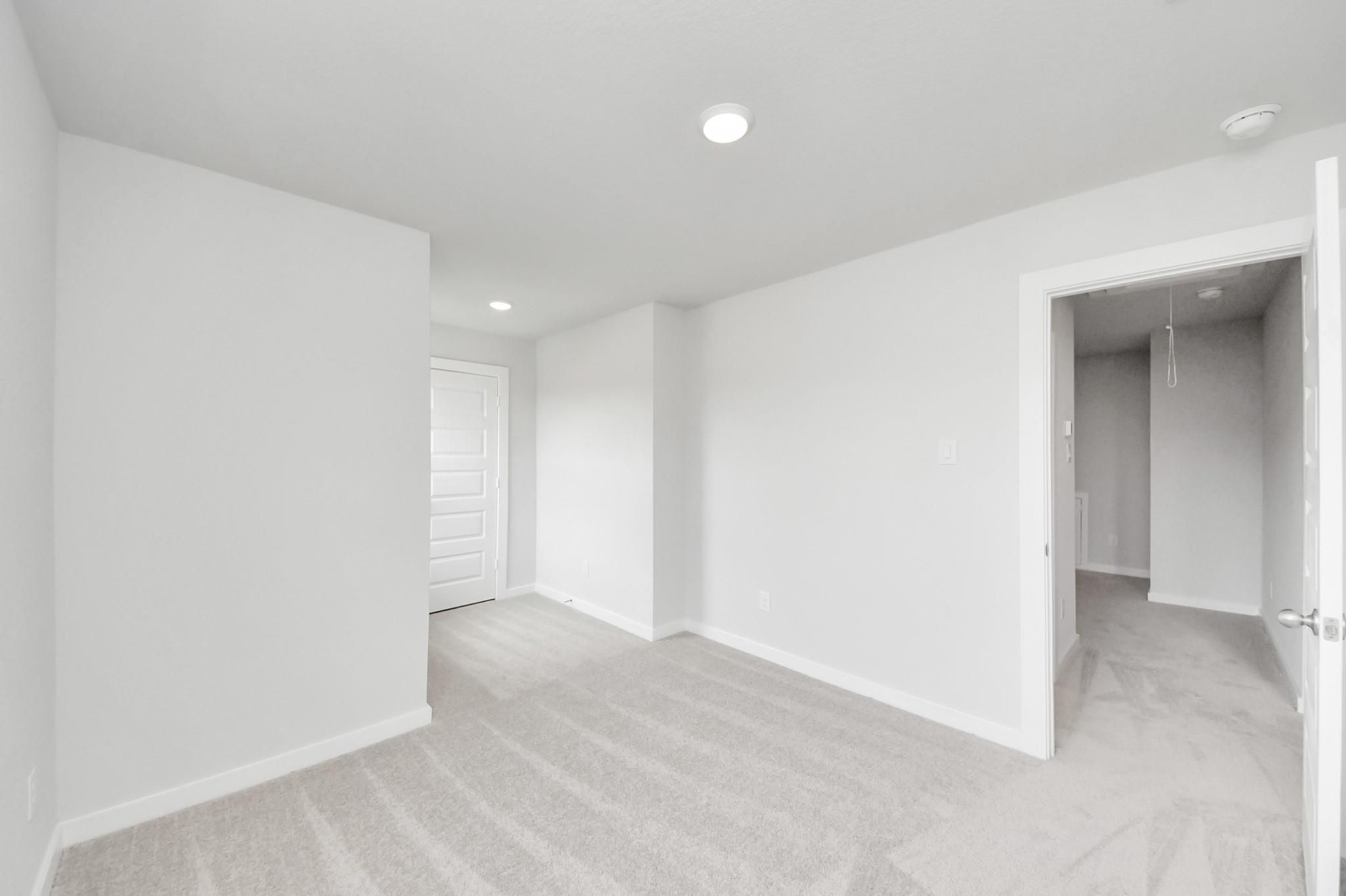 Bright and spacious secondary bedroom with plush carpet in The Blanco E floor plan at Caney Creek Place, Conroe, Texas.