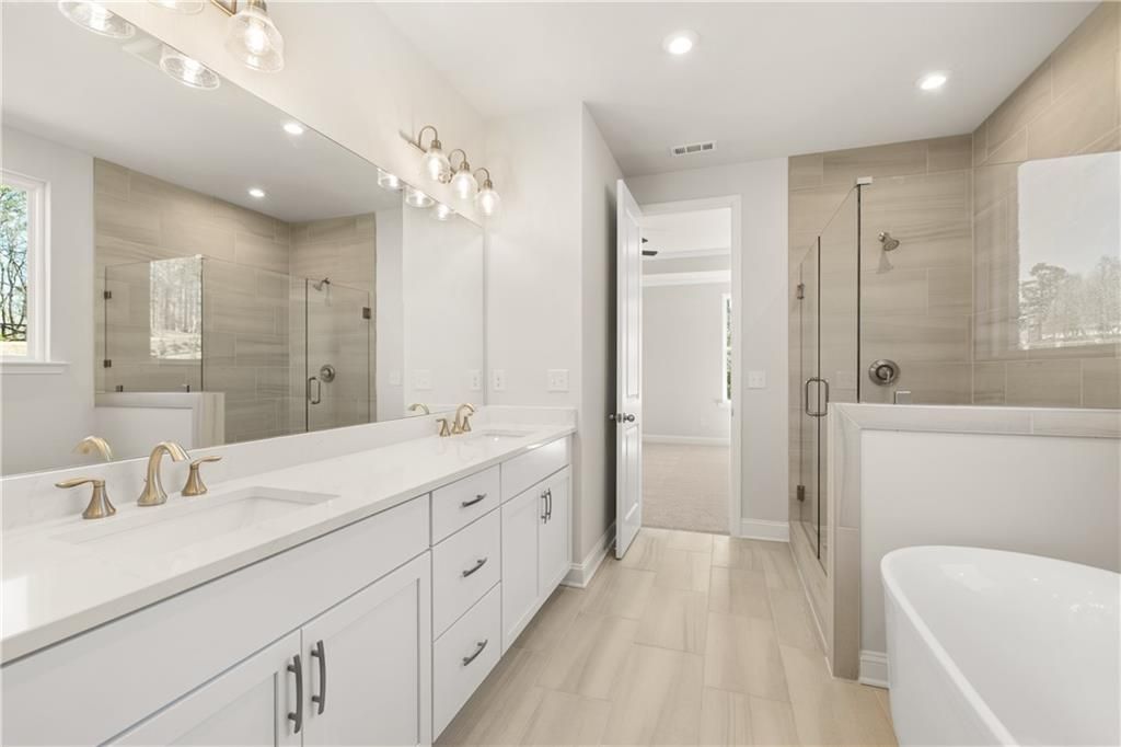 Elegant master bathroom featuring double white quartz vanity, glass shower, freestanding tub in Davidson Homes The Danbury C, Buford, GA