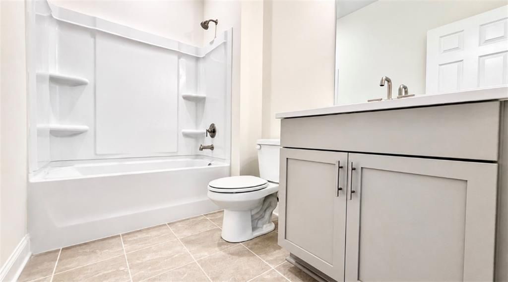 Modern bathroom with white tub-shower combo and vanity in The Hickory C floor plan at Wehunt Meadows, Hoschton, Georgia.