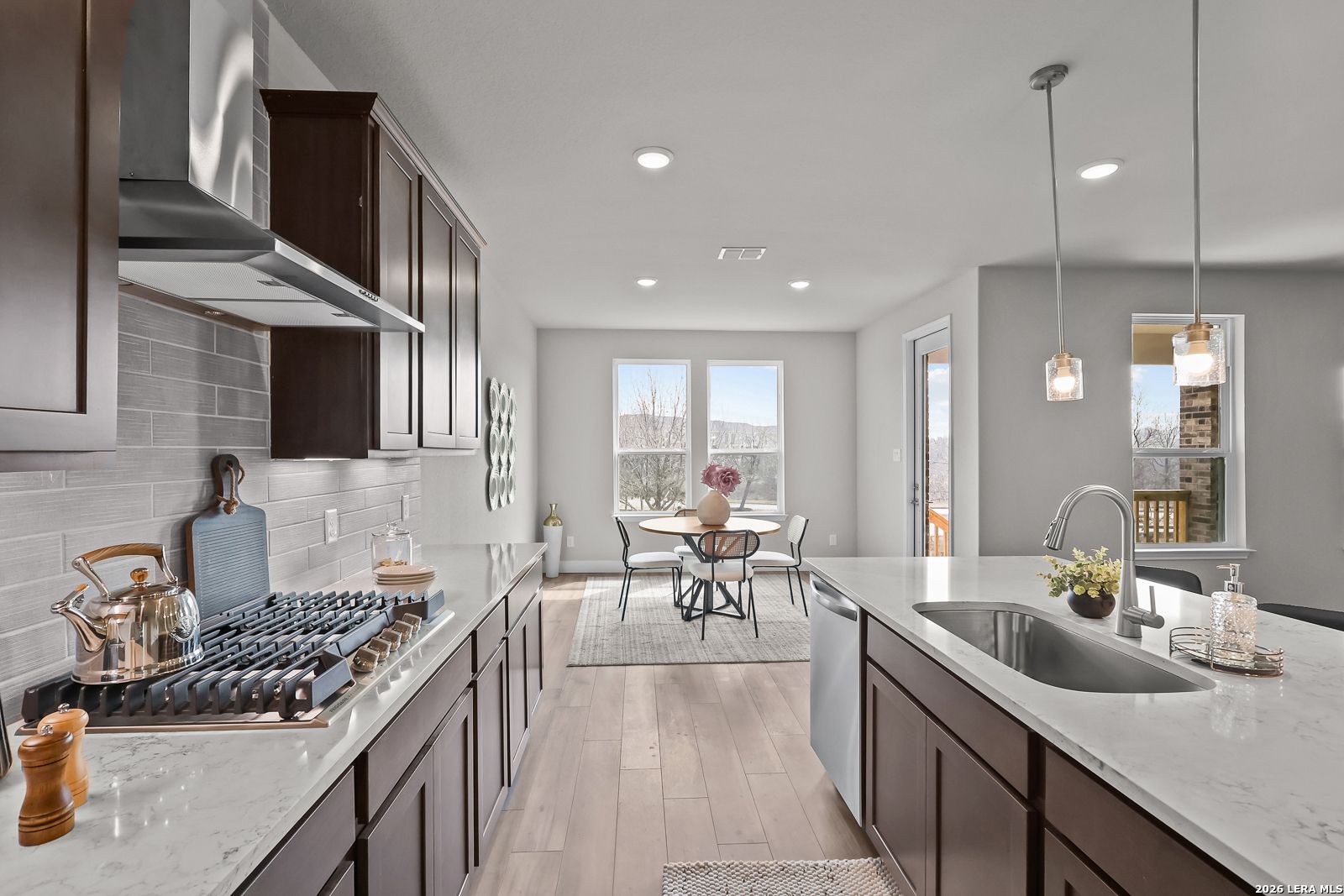 Modern open-concept kitchen with white quartz island, subway tile backsplash, and dining nook in Davidson Homes The Rockford G, Ladera, San Antonio