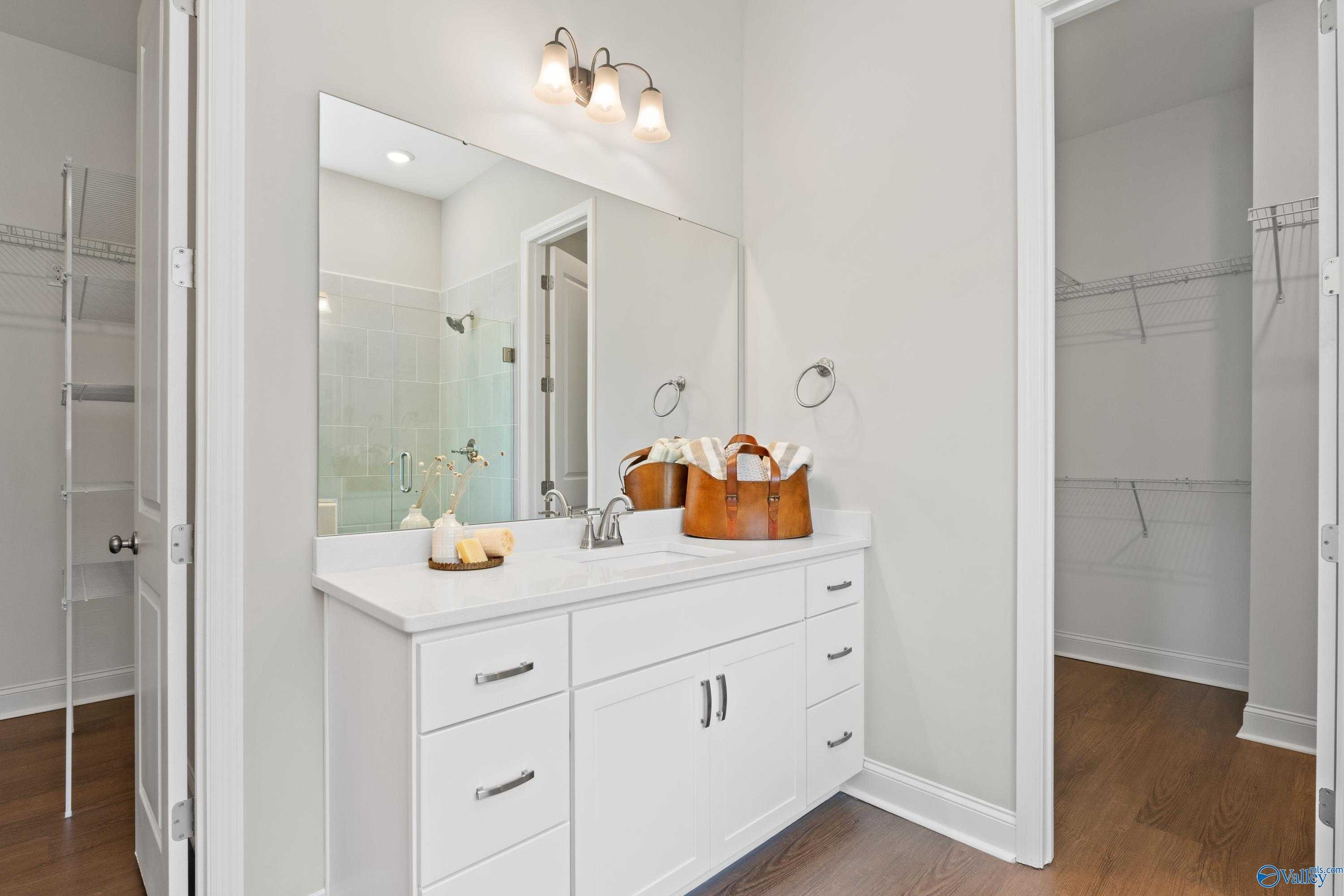 Elegant master bathroom with white double vanity, frameless glass shower, and walk-in closet in Evermore Homes The Haven, Owens Cross Roads