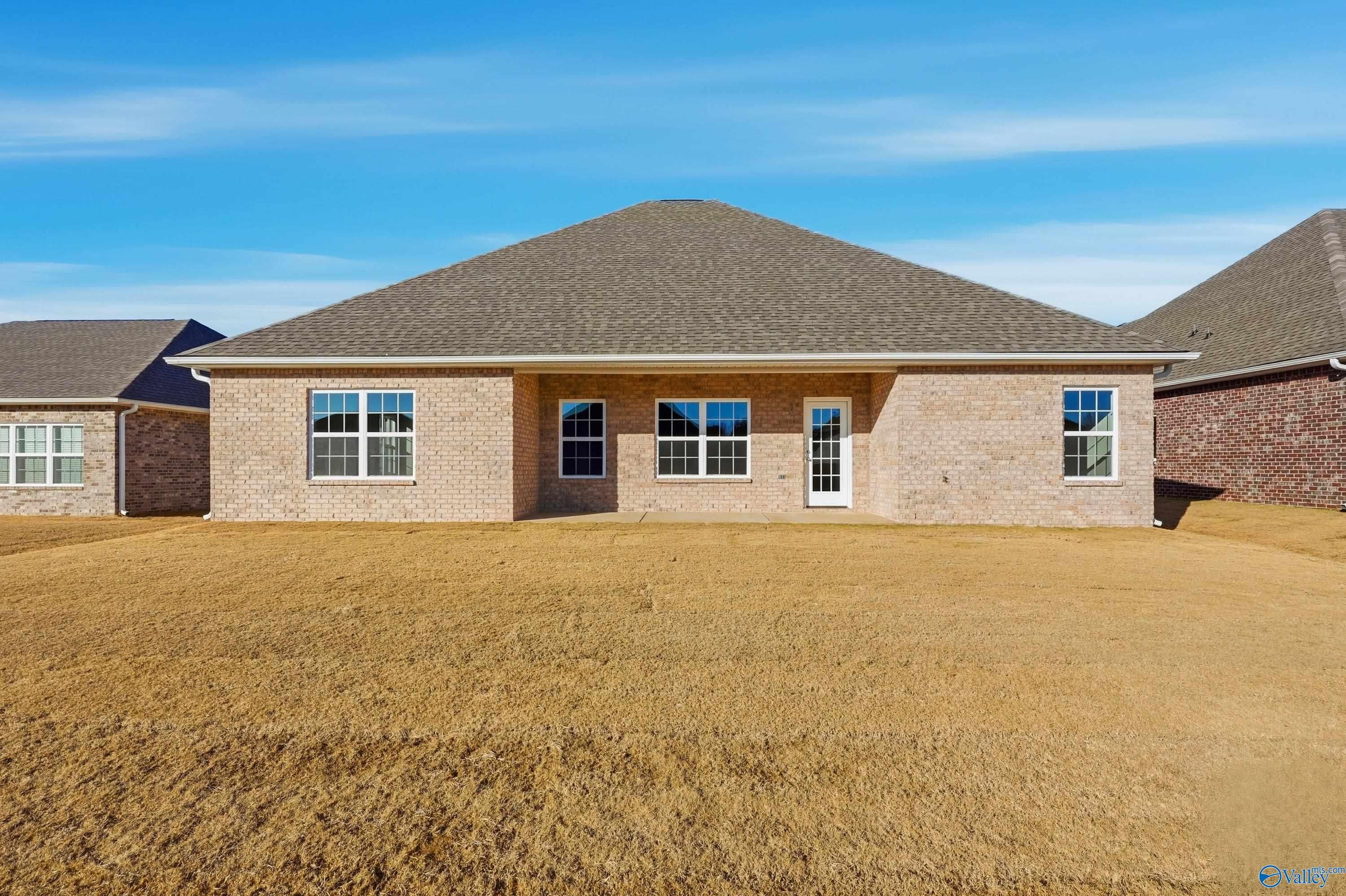 Front view of single-story brick home with gabled roof, 2-car garage, and expansive yard in Kendall Downs, Toney, Alabama - Davidson Homes The Lanier