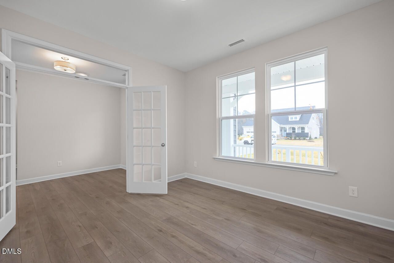 Bright sunroom with hardwood floors, French doors, and large windows overlooking porch in 4-bedroom Davidson Homes The Cypress D II, Angier, NC