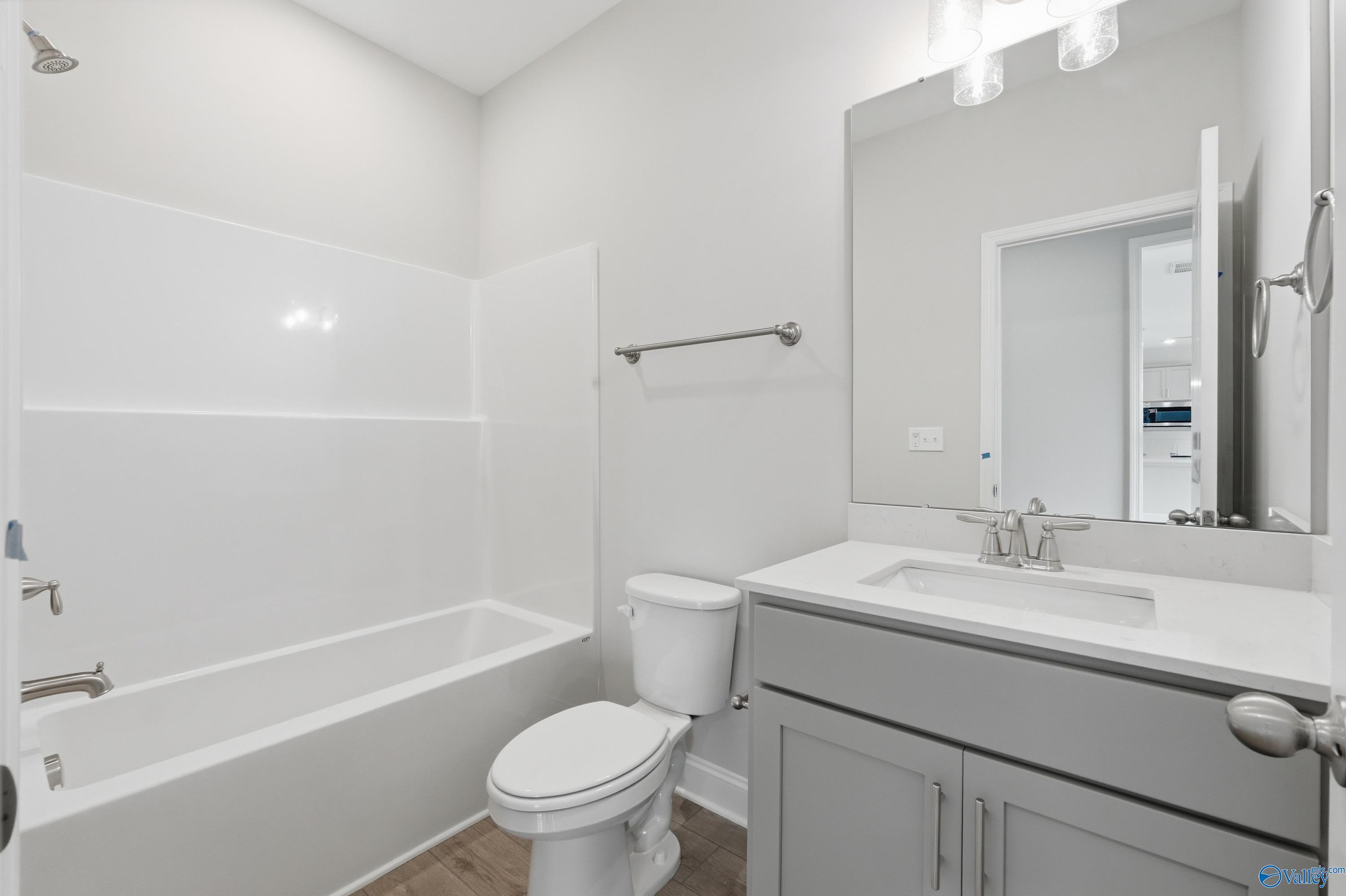 Bright secondary bathroom with white tub-shower combo, gray shaker vanity, and toilet in Davidson Homes Shelby B, New Market, Alabama
