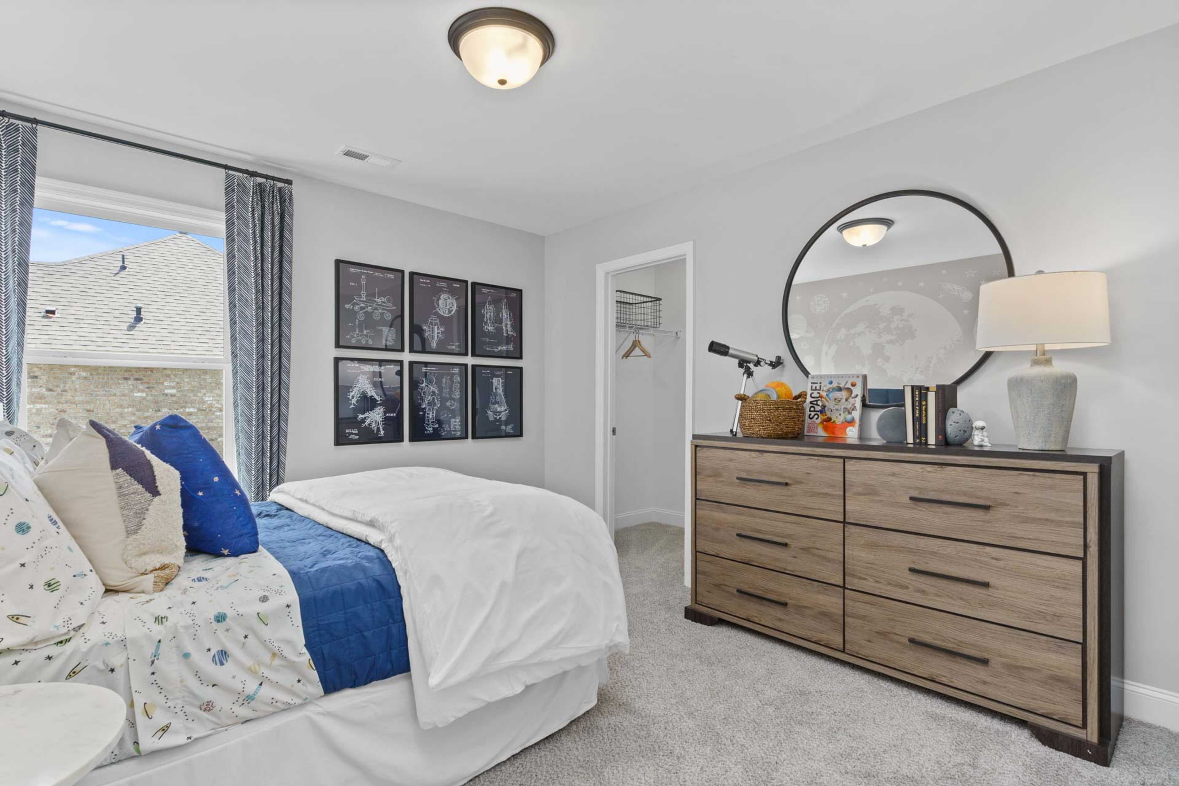 Cozy bedroom at Creek Grove in New Market Alabama with white bed blue pillows wooden dresser round mirror and large window