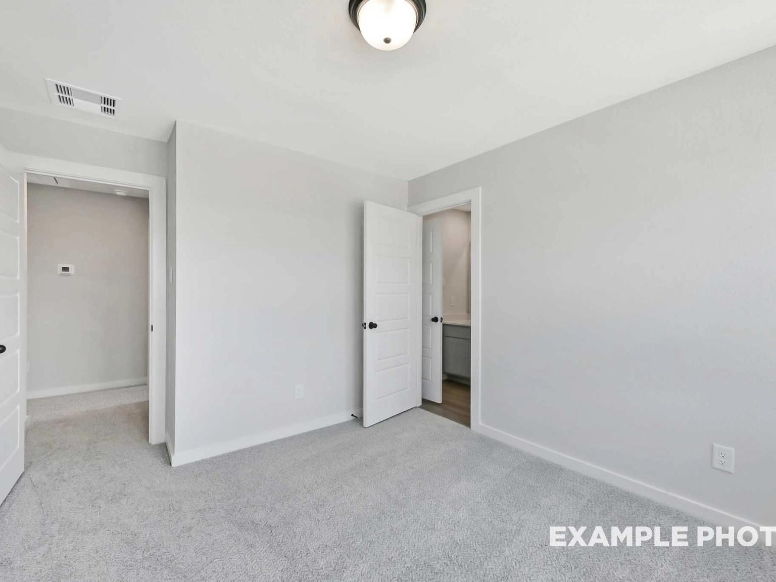 Spacious bedroom with plush carpet and en-suite bathroom in The Sequoia C floor plan at Sundance Cove, Crosby, Texas.