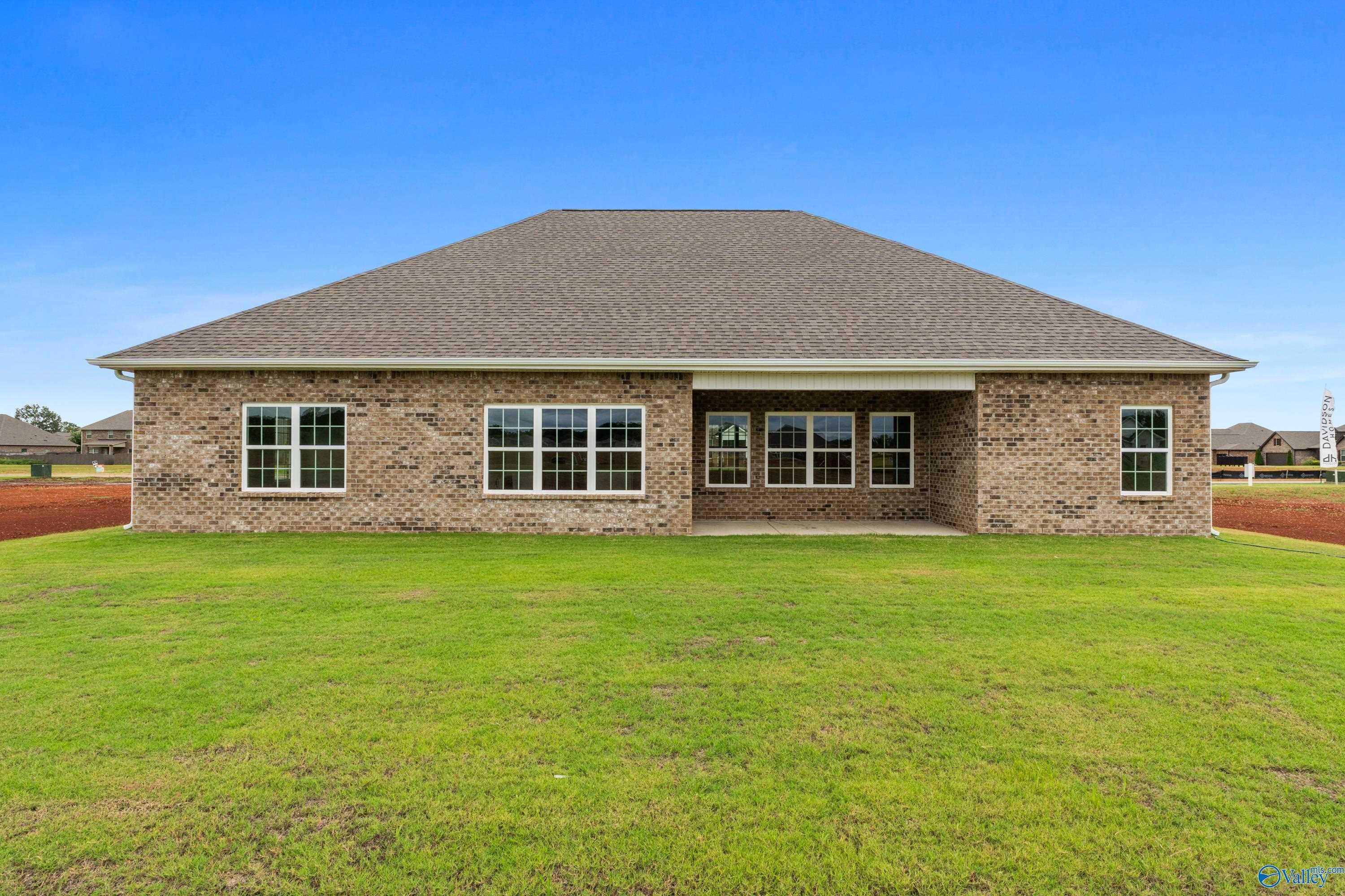 Brick single-story home with gabled roof, large windows, covered patio, and green lawn in Briercreek, Meridianville, Alabama