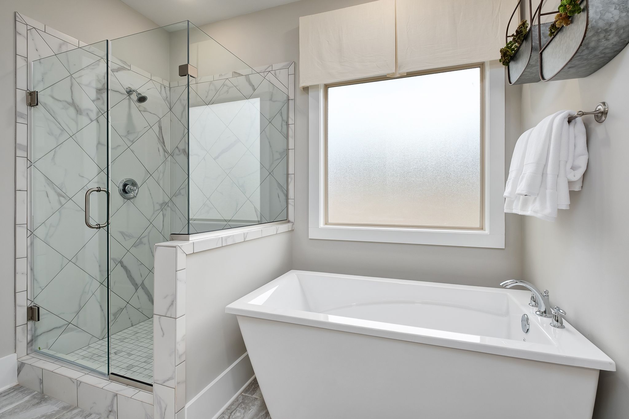 Luxurious master bathroom at Chimney Creek in Hampton Cove Alabama with glass shower marble tiles and freestanding tub