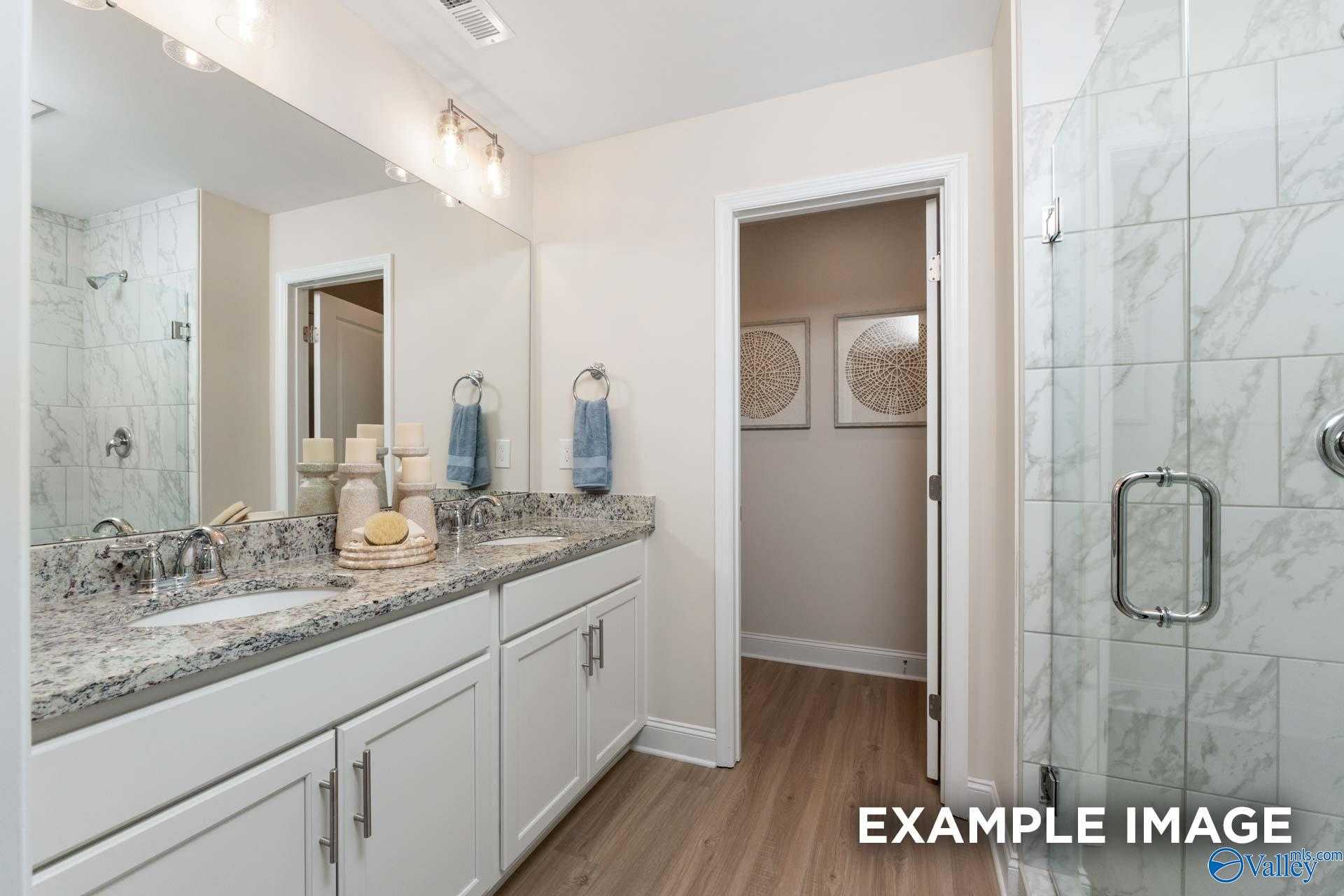 Modern master bathroom with double granite vanity, frameless glass shower, and walk-in closet in Davidson Homes The Camden B, Huntsville AL