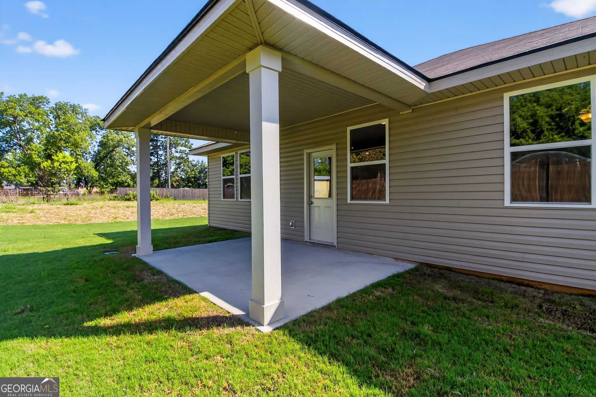 Covered side patio with columns on beige 4-bedroom Luna home by Evermore in Ivy Glen, Perry, Georgia