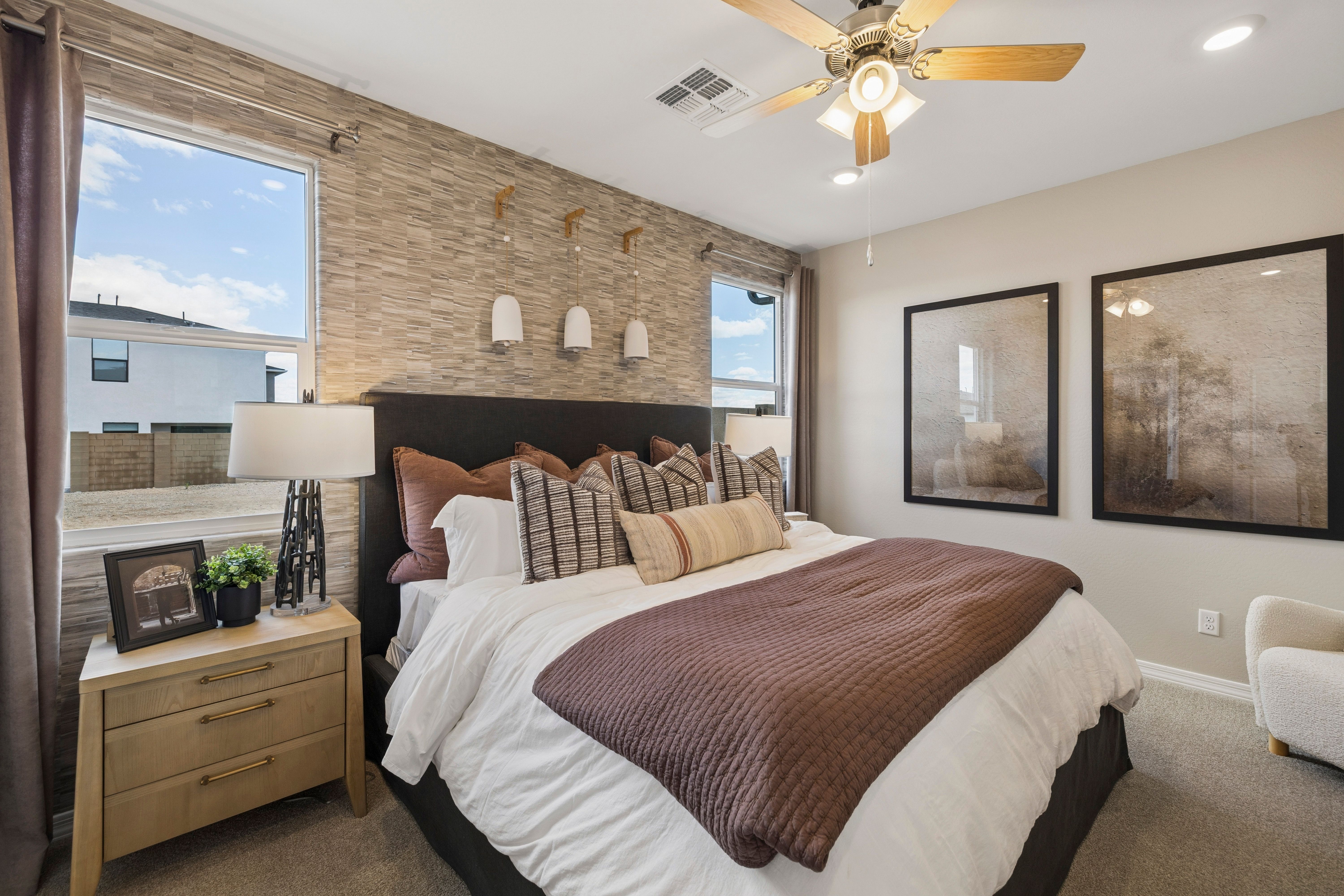 Master bedroom at Senator Cottages in Prescott AZ featuring king bed, textured accent wall, ceiling fan, and large windows