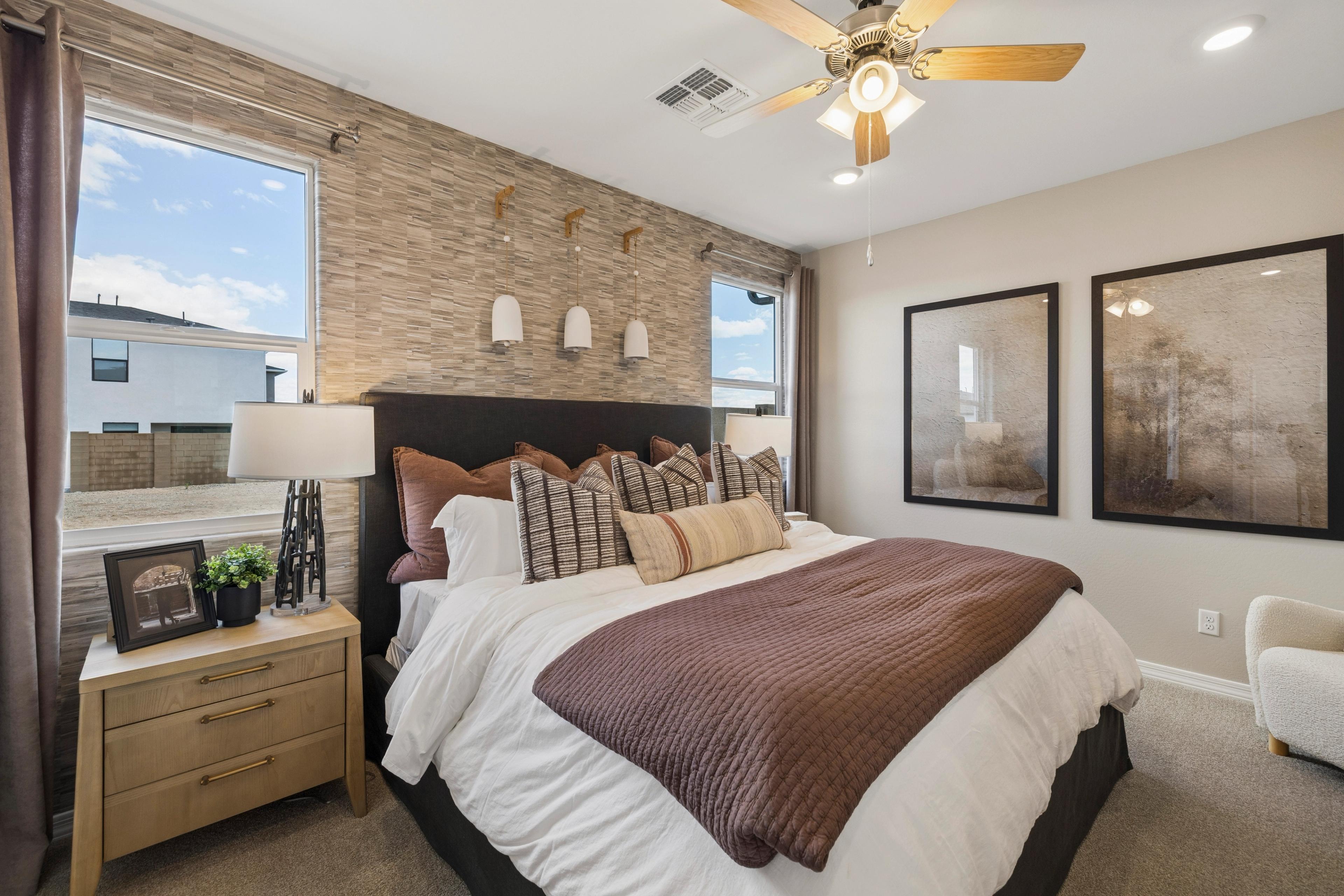 Master bedroom at Senator Cottages in Prescott AZ featuring king bed, textured accent wall, ceiling fan, and large windows