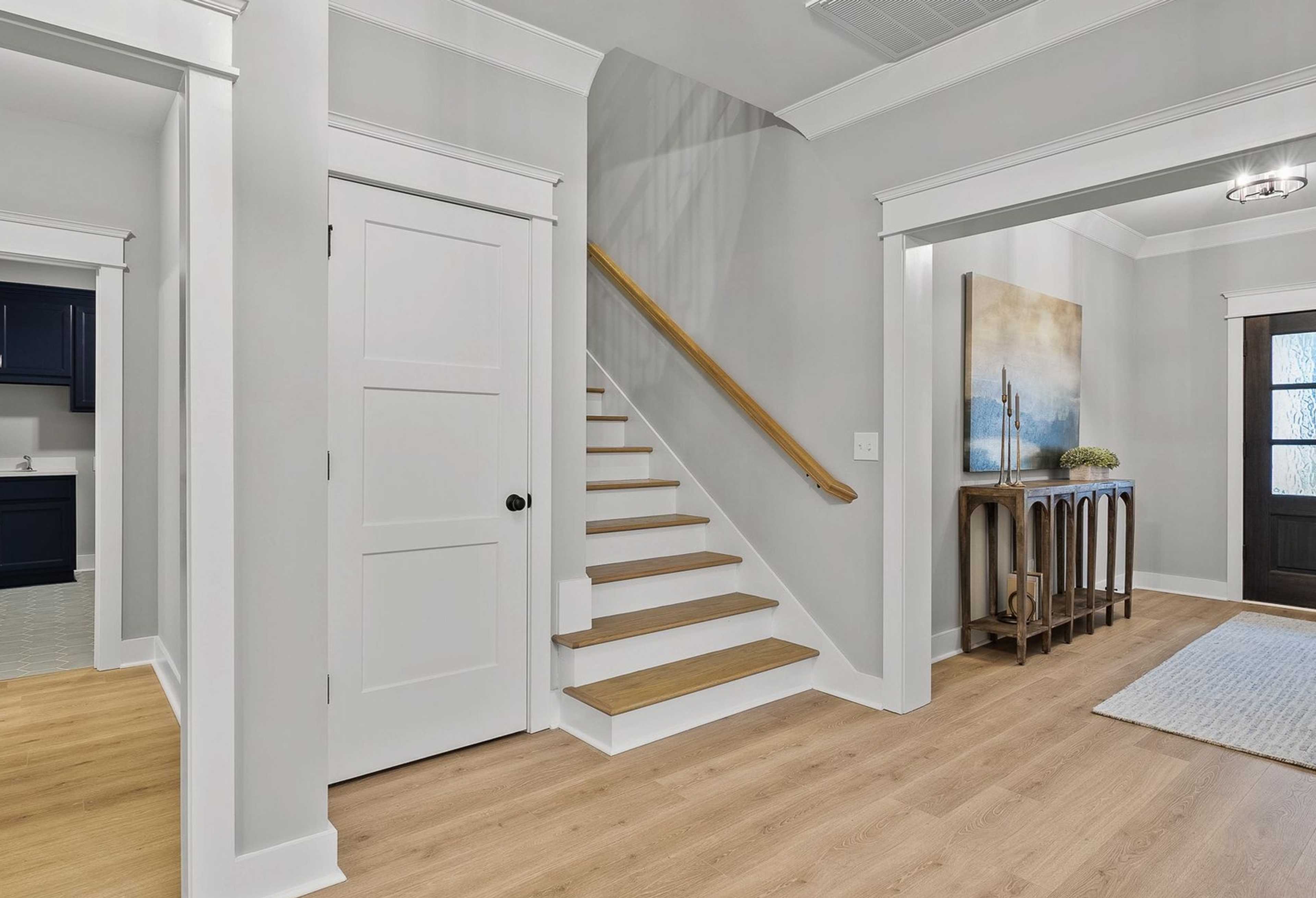 The Oxford home foyer with oak staircase, navy powder room, console table, and mahogany entry door