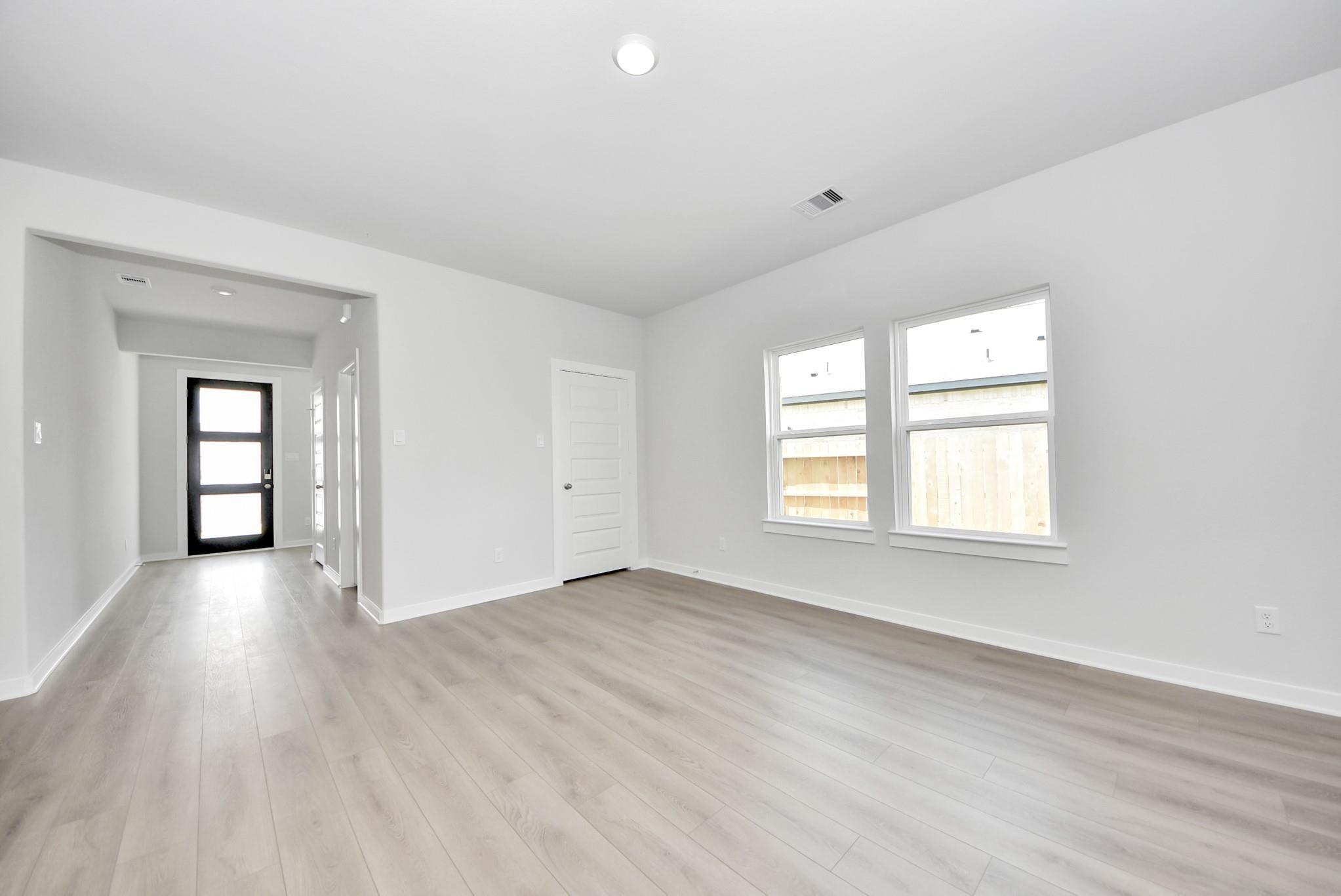 Bright, open-concept room with light wood-style flooring in The Verano B floor plan by Davidson Homes in Sunterra, Katy.