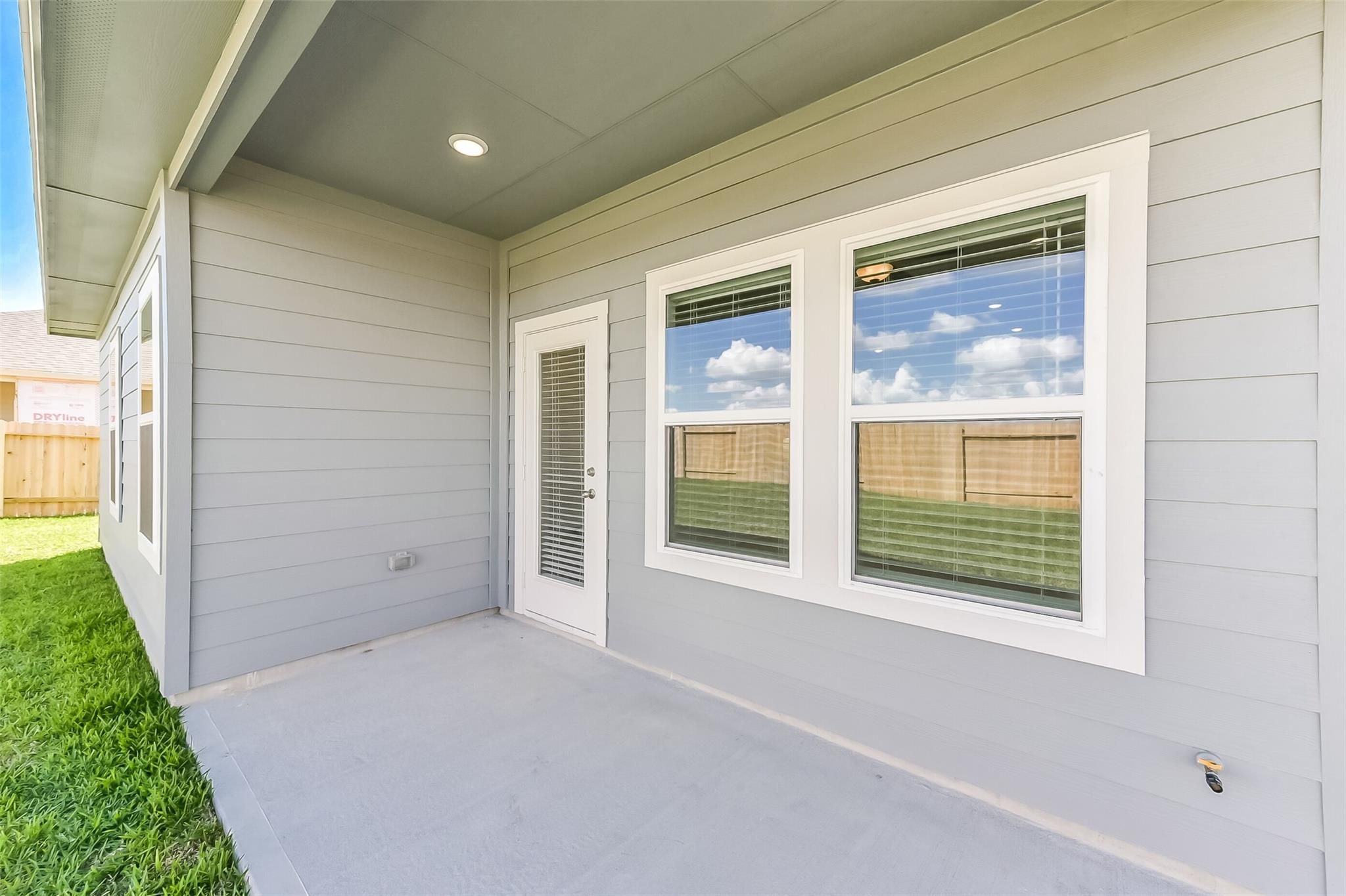 Covered patio with glass door, large windows, and lush green lawn in Davidson Homes The Costa B 3-bedroom home, Dayton, Texas